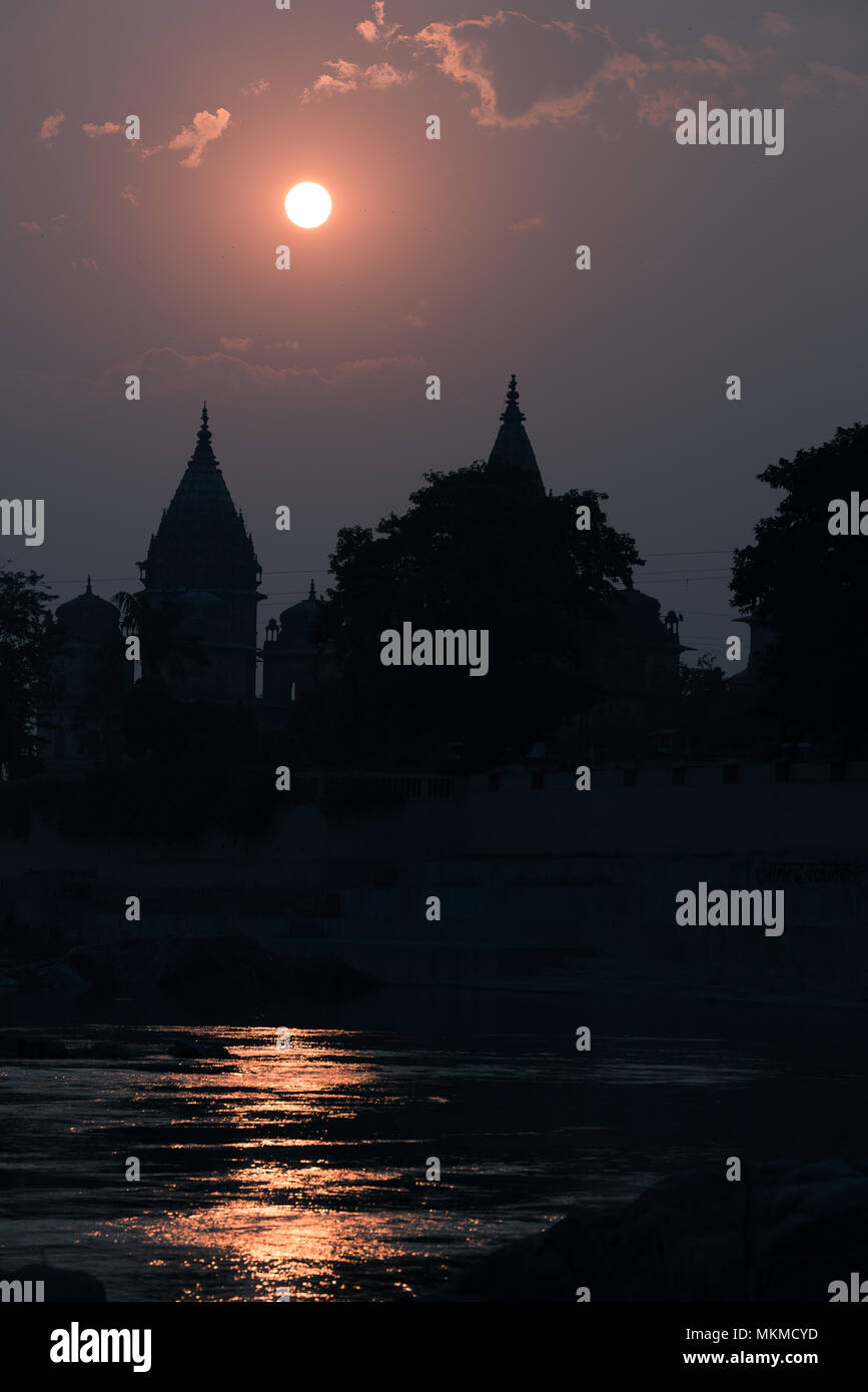 Gebäude Silhouette bei Sonnenuntergang in Indien. Sun Reflexion auf dem Fluss. Travel Concept. Orchha Tempelanlage. Stockfoto