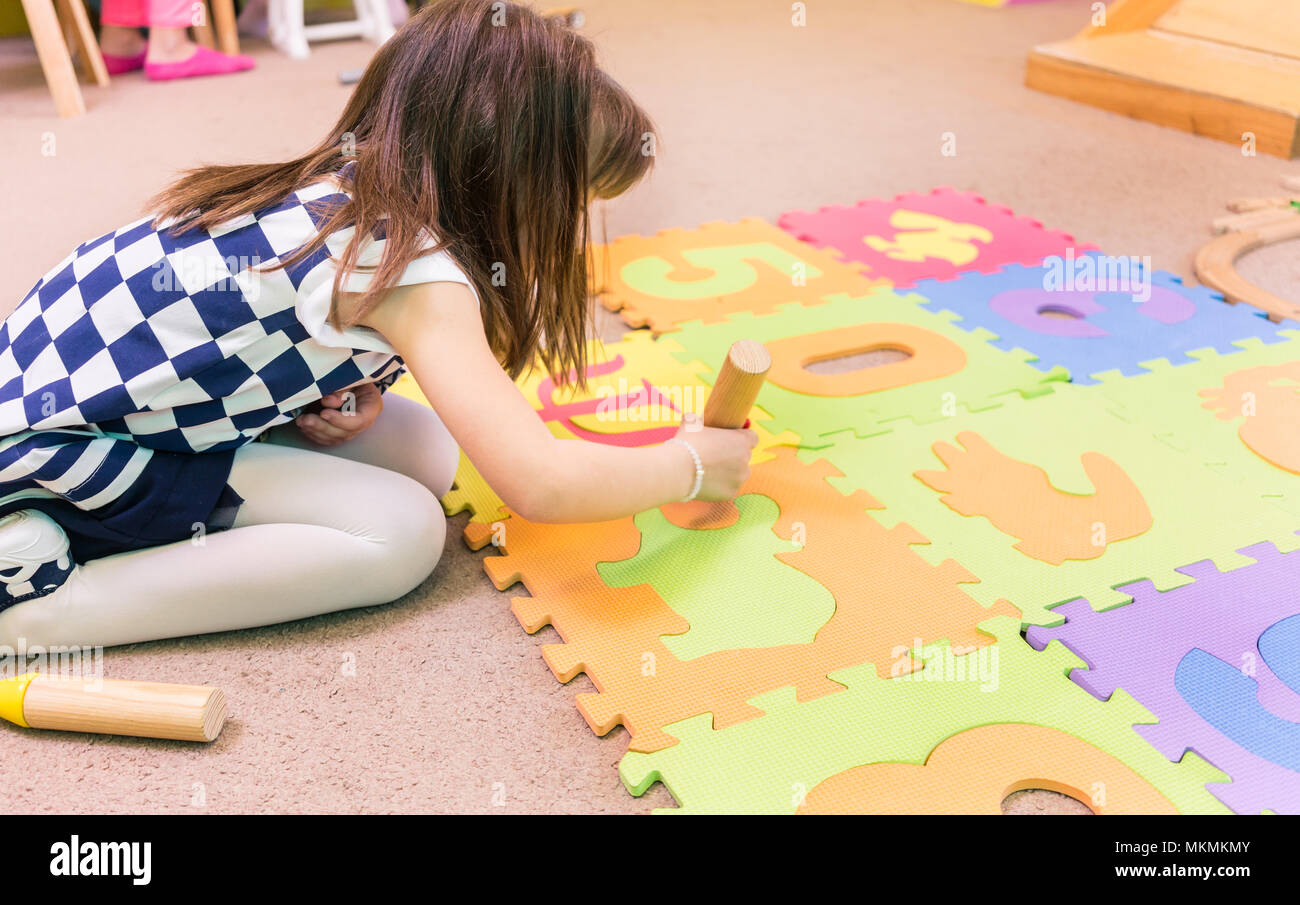 Cute Pre-school Mädchen spielen mit einem bunten Puzzle spielen mat Stockfoto