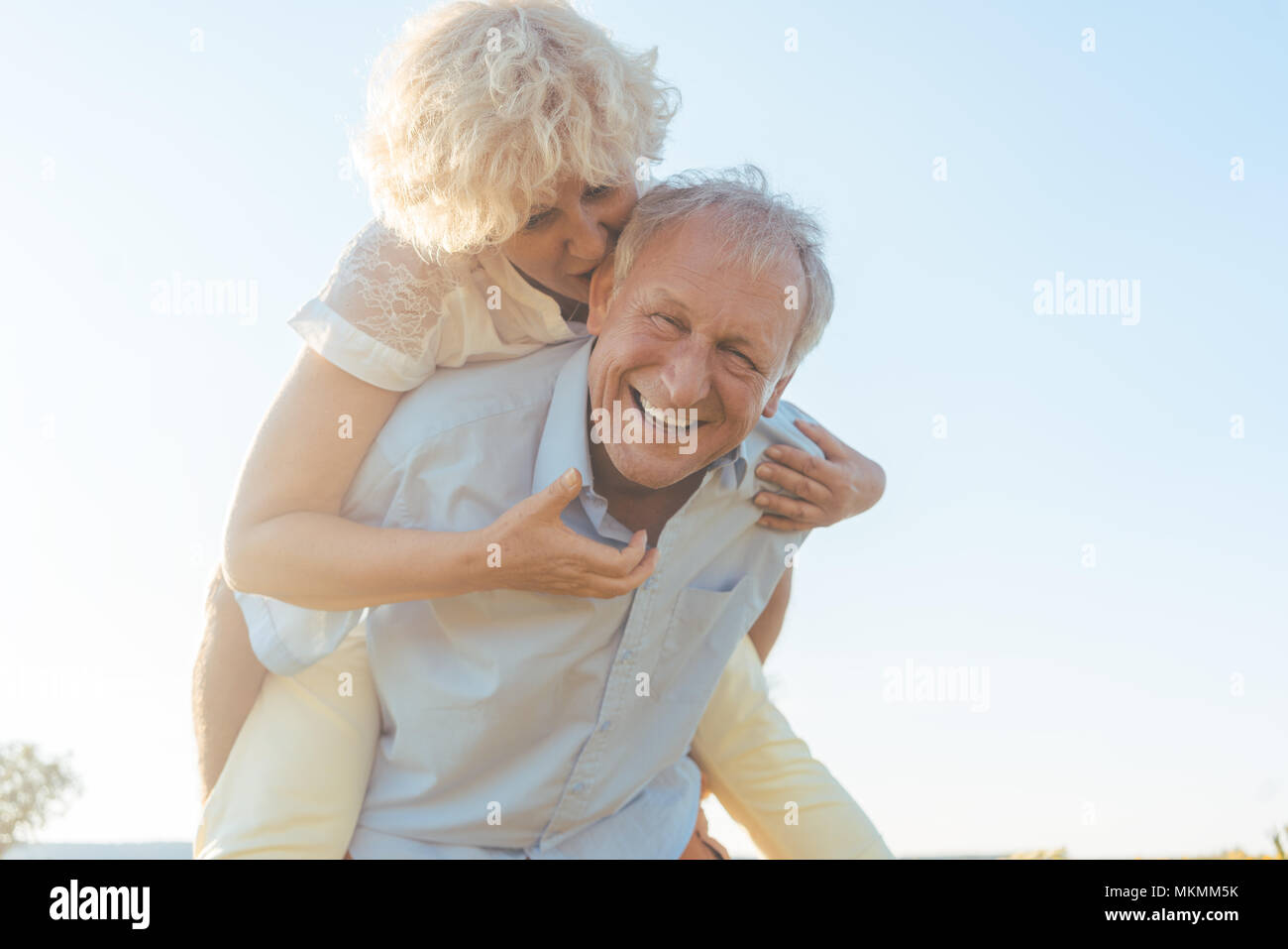 Gerne älterer Mann Lachen, während sein Partner tragen auf dem Rücken Stockfoto