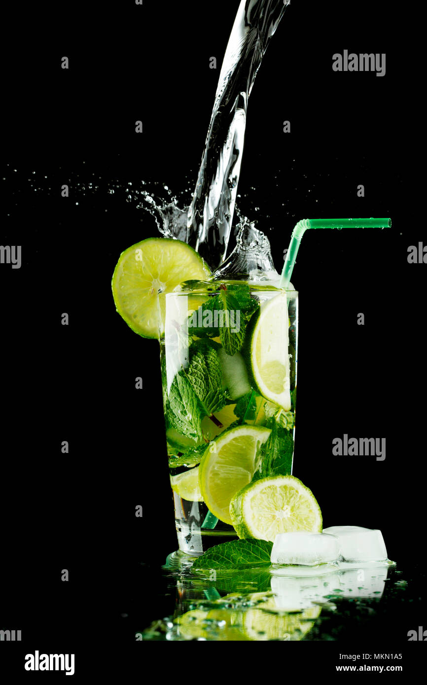 Gießen frischen Mojito Cocktail im Glas auf schwarzem Hintergrund isoliert Stockfoto