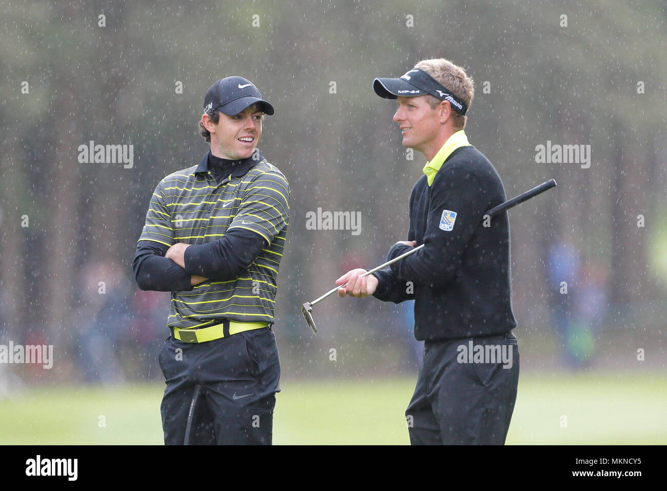 Rory McIlroy mit Luke Donald im Regen auf dem 13 Grün während der dritten Runde der europäischen Tour 2014 der BMW PGA Championship in Wentworth Golf Club, Virginia Water, Surrey, England. 24. Mai 2014 --- Bild von: © Paul Cunningham Stockfoto
