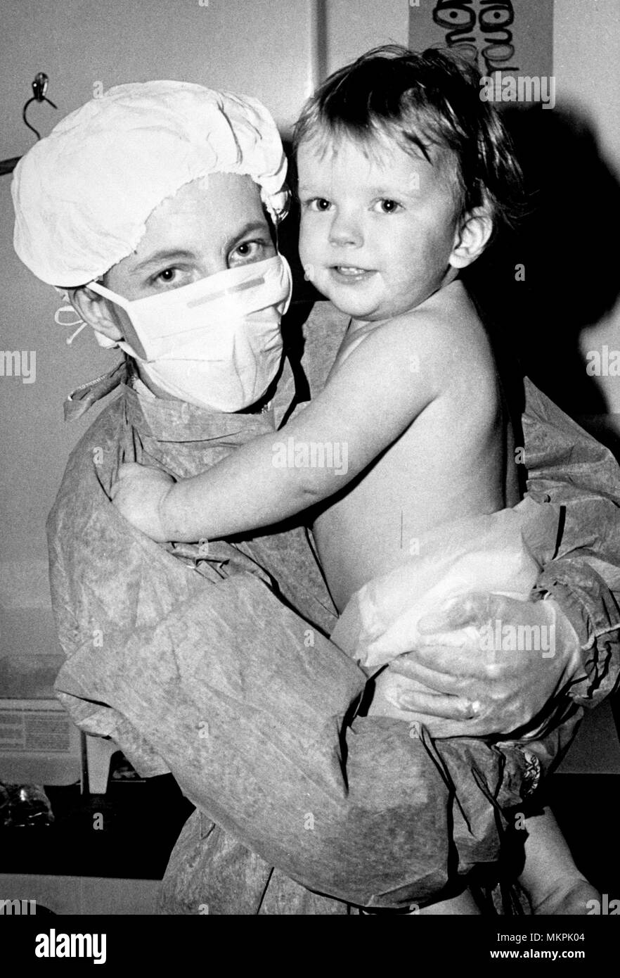 Das Tragen einer Schutzmaske ist Elisabeth Bostic, 28, wer hält Ihr 21 Monate alter Sohn Simon an der Westminster Children's Hospital. Simon zeigt keine Zeichen der Ablehnung des Knochenmark transplantiert er 11 Tage vor hatte. * Provinz nur verwenden. * BBC ITN und AP heraus Stockfoto