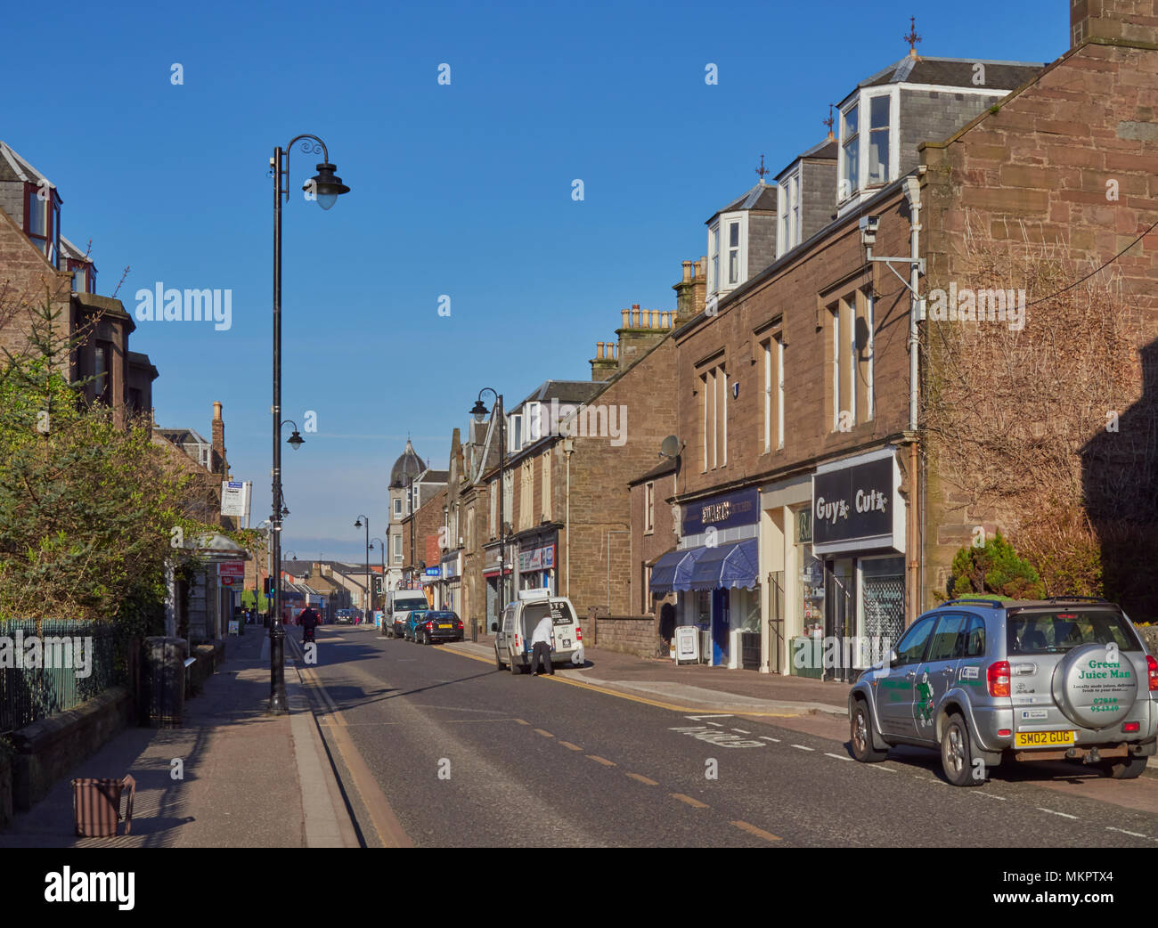 Auf der Suche Carnoustie High Street mit einem Radfahrer vorbei, und ein Ladenbesitzer laden seinem Van. Carnoustie, Angus, Schottland. Stockfoto