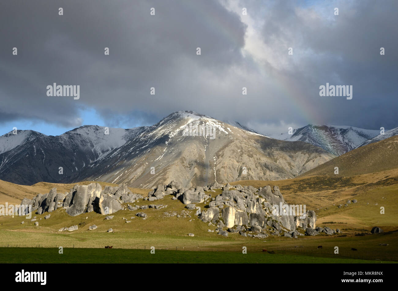 Ein schwaches Rainbow hängt über die kalksteinfelsen in der Castle Hill, Südinsel, Neuseeland Stockfoto