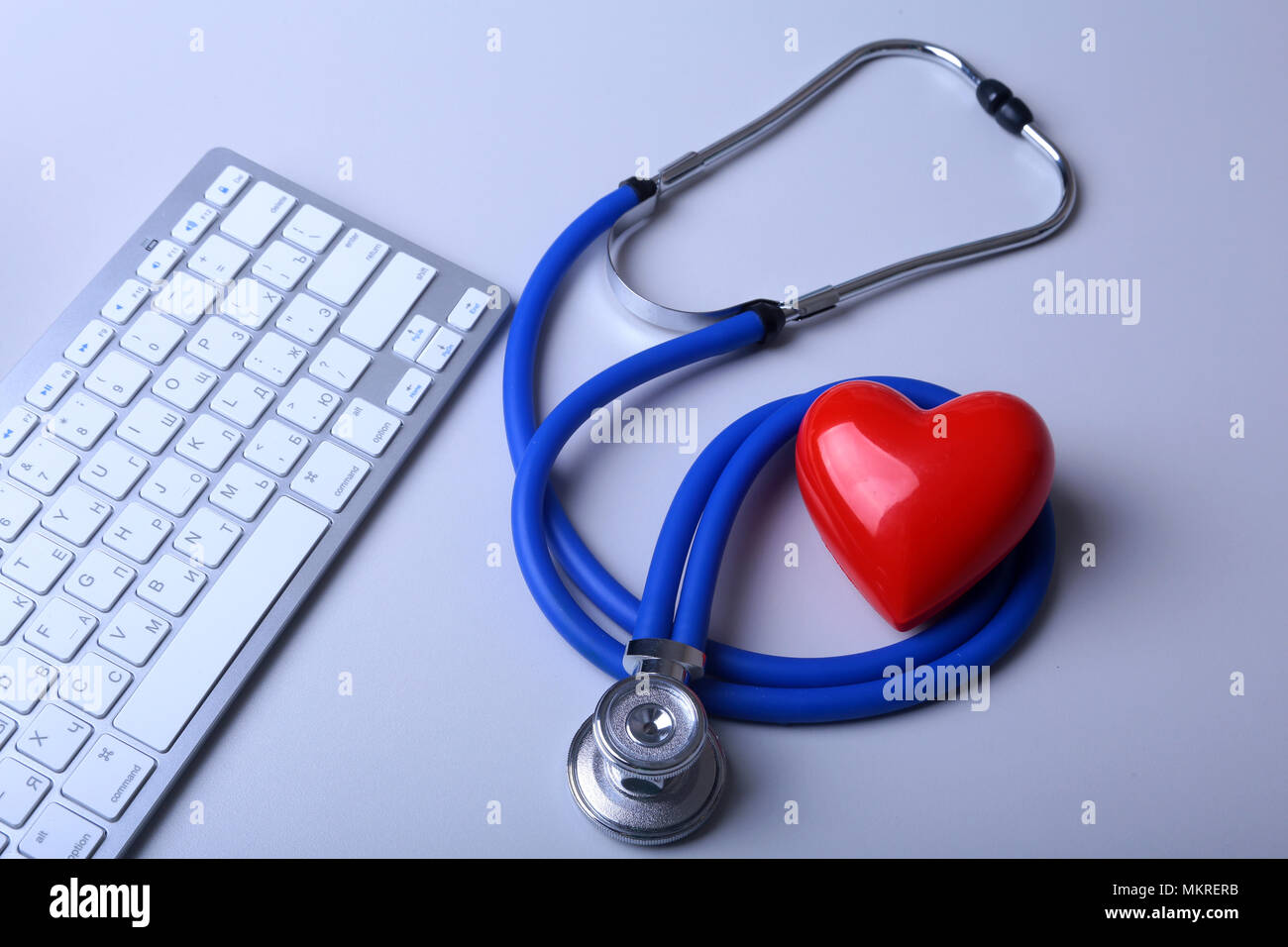 Eine medizinische Stethoskop mit roten Herzen in der Nähe von einem Laptop auf einen hölzernen Tisch. Stockfoto