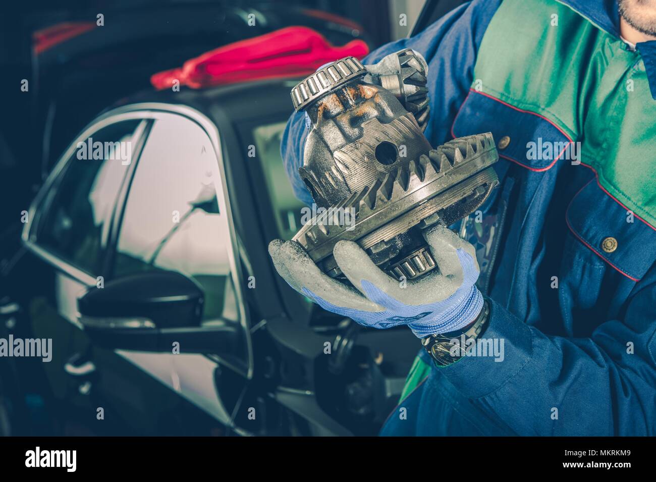Kaukasische Automechaniker in seinem 30s mit Teil der Auto Differential in Händen. Fahrzeug Service Thema. Stockfoto