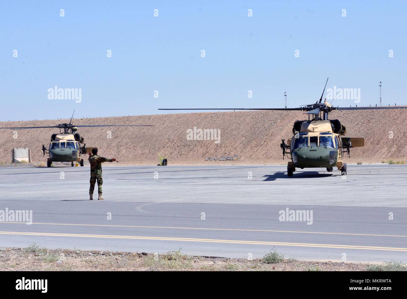 Einen afghanischen Luftwaffe Mitglied leitet zwei UH-60 Blackhawks, wie sie sich vorbereiten, für die erste Afghanische zu nehmen - die Mission auf diesem Flugzeug Mai 8, 2018 Led, Kandahar Air Field, Afghanistan, 8. Mai 2018. Die Mission, die zur Unterstützung der Wahlen war, ereignete sich nur einen Tag nachdem die Mannschaften von Mission Qualifizierung Ausbildung absolvierte. (U.S. Air Force Foto/1 Lt Erin Recanzone). () Stockfoto
