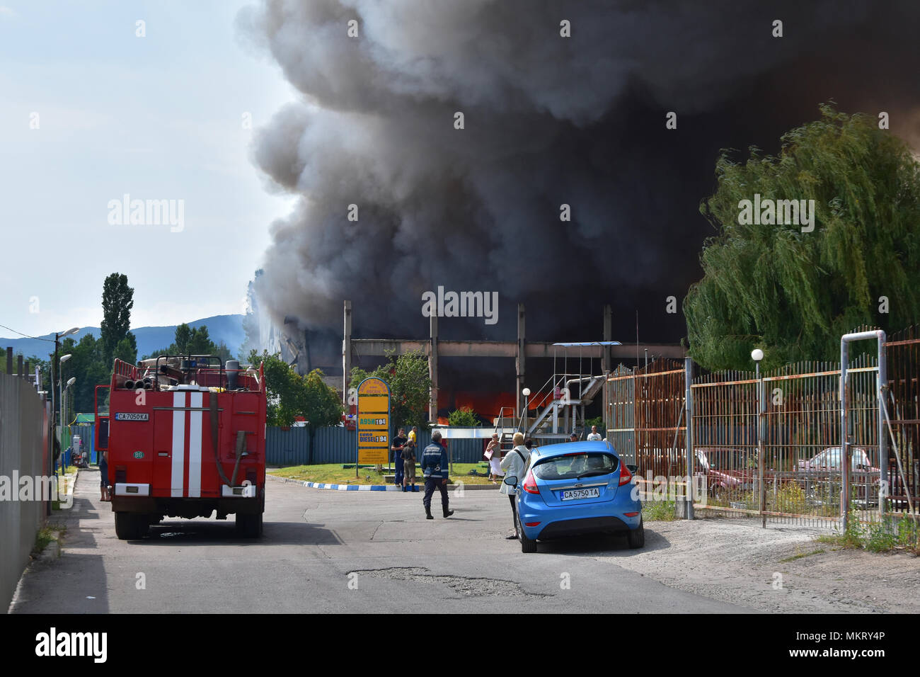 Sofia, Bulgarien - 15. Juli 2017: Großbrand in Kleidungsstück Lager direkt neben einer Tankstelle in Kazichene - Sofia Stadtrand. Feuerwehrmänner einfach ankommen Stockfoto