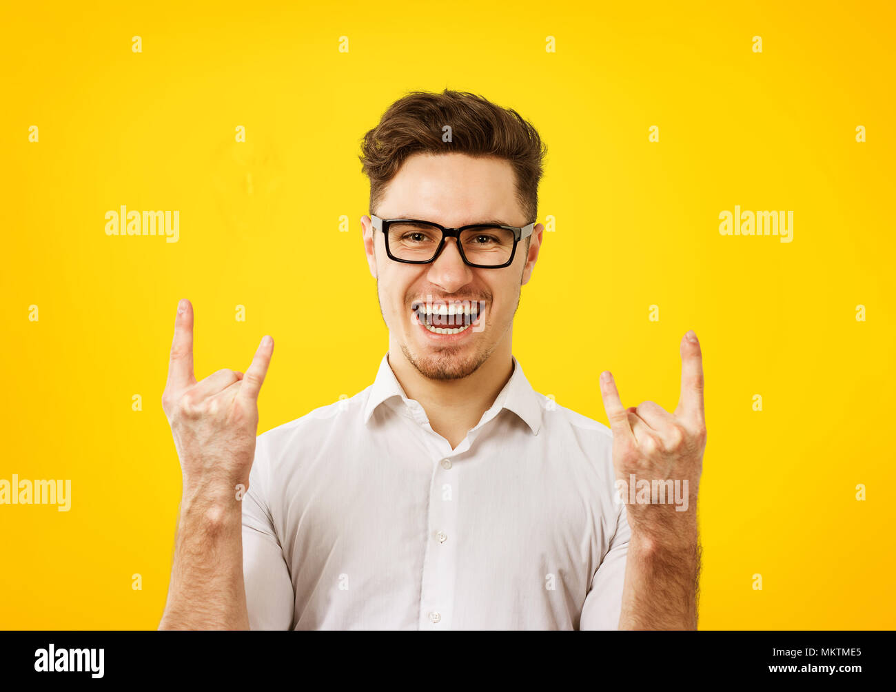 Junge hipster Mann in Gläser holding Fäuste oben coole Geste Zeichen feiert Sieg auf orange gelb hinterlegt. Stockfoto