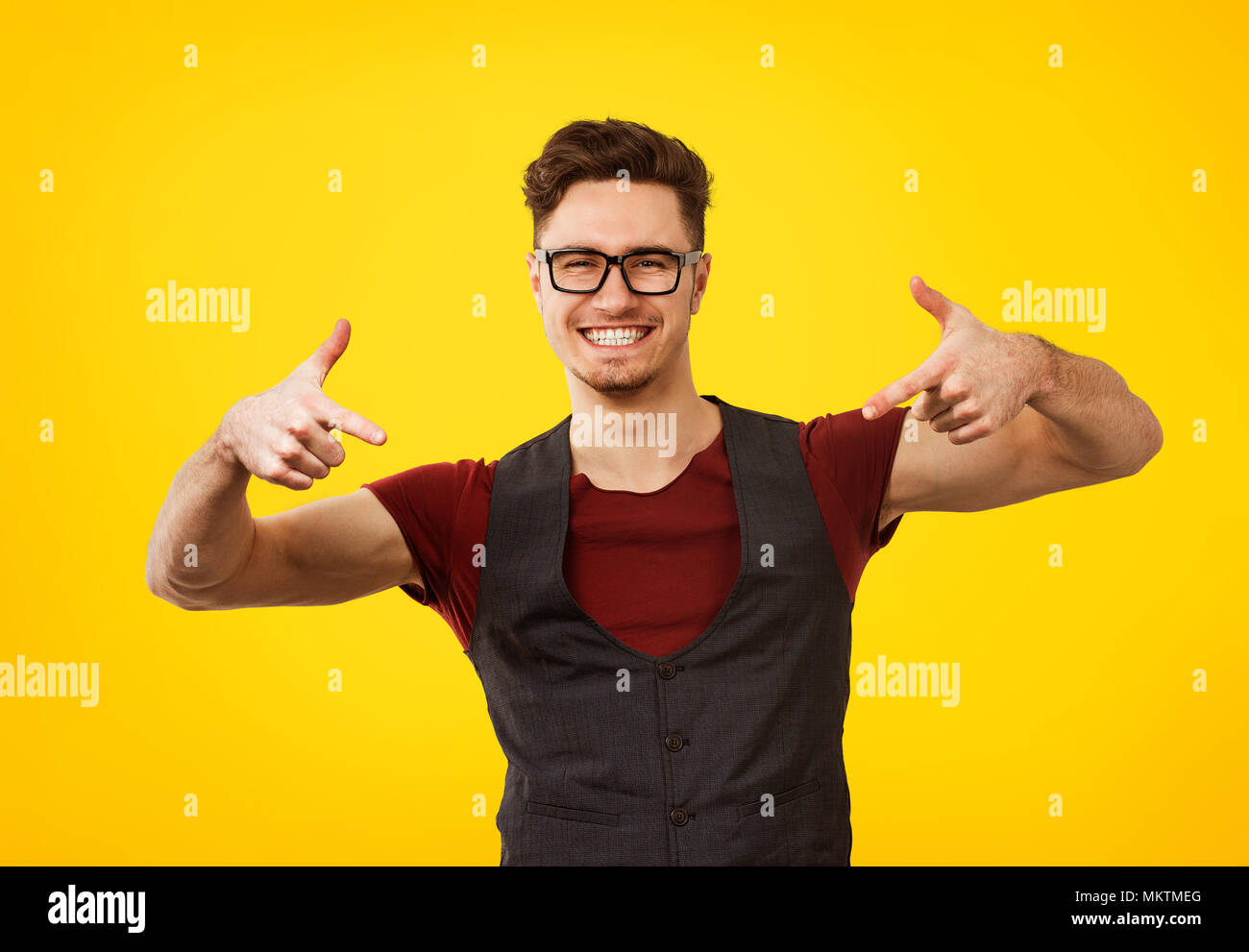 Portrait des jungen Mannes im stilvollen cooles Outfit und Gläser ausdrücklich posiert auf gelbem Hintergrund Stockfoto