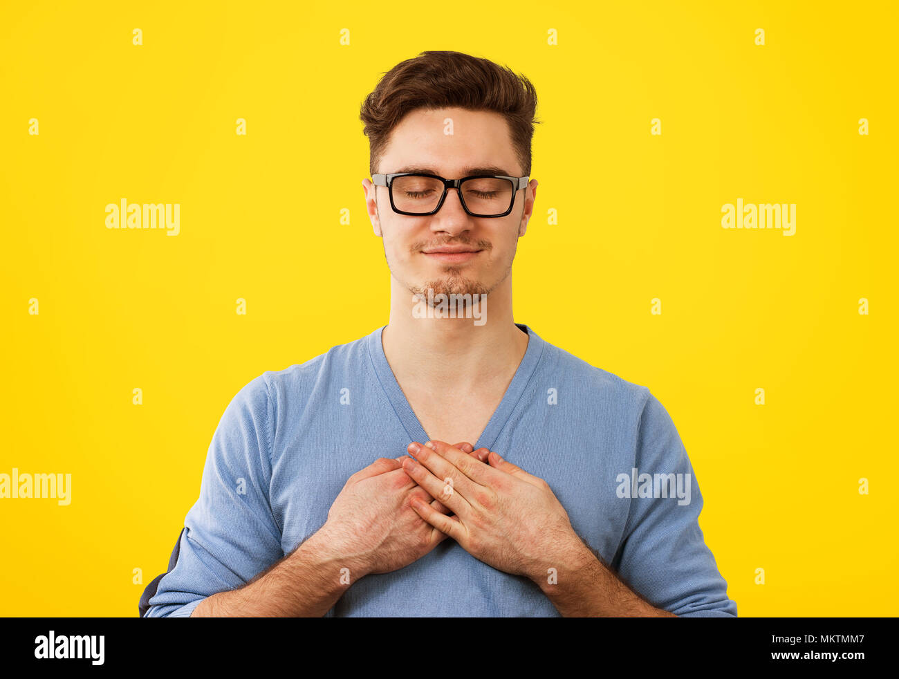 Treuer Mann mit geschlossenen Augen hält die Hände auf der Brust in der Nähe von Herz, Freundlichkeit, aufrichtige Gefühle ausdrückt, die gutherzige. Körpersprache Gefühle Stockfoto