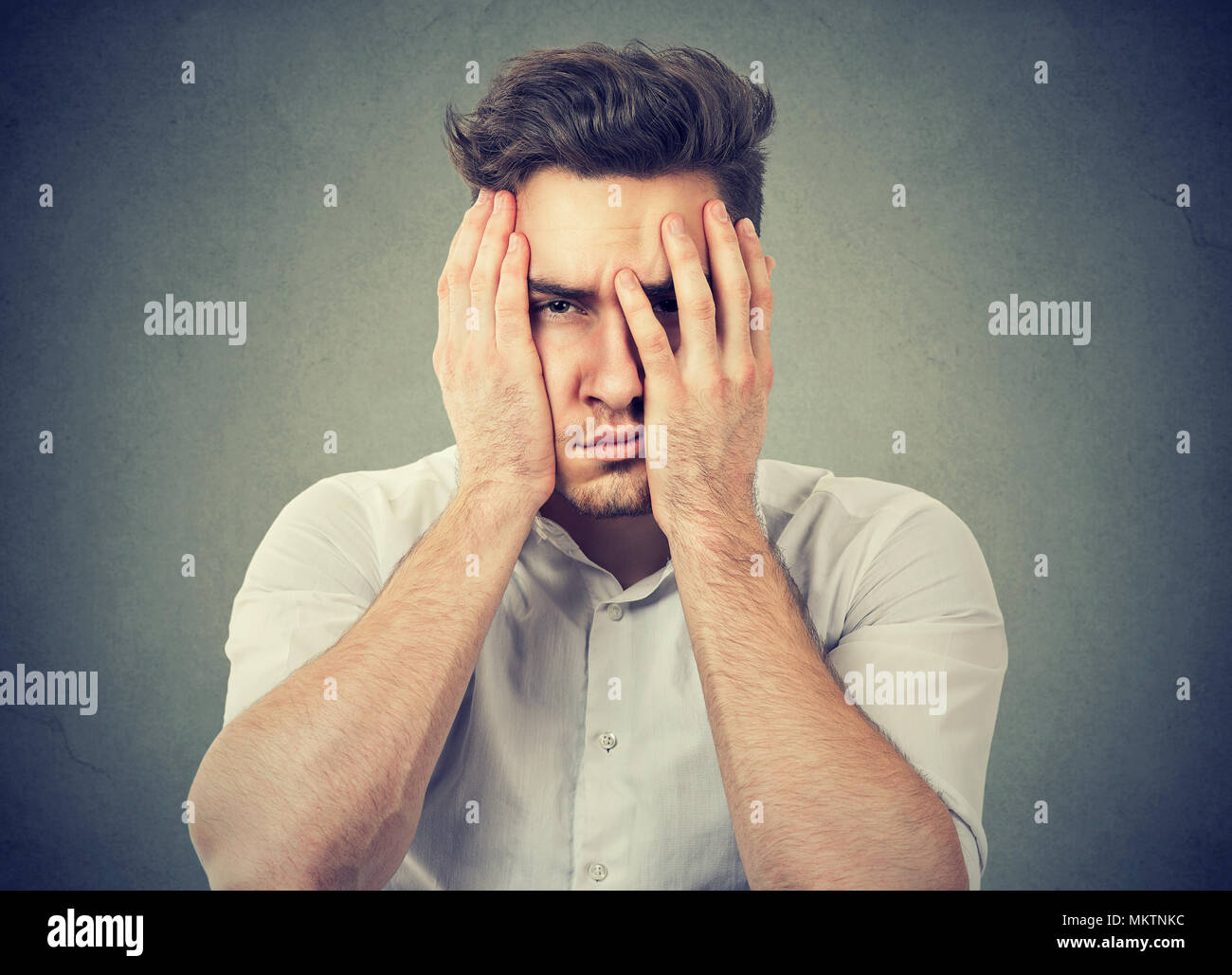 Junge frustrierter Mann das Gesicht mit den Händen auf der Suche unglücklich an Kamera Probleme im Leben Stockfoto