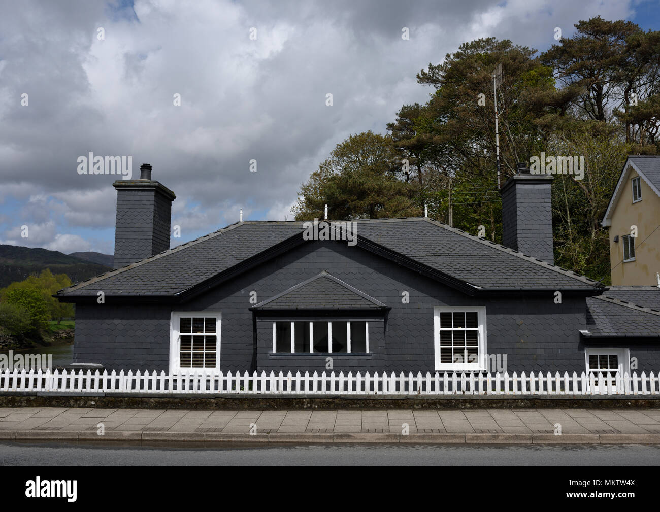 Schieferhaus mit zwei Schornsteinstapeln und weißen Holzpfählen Fence Porthmadog North wales großbritannien Stockfoto