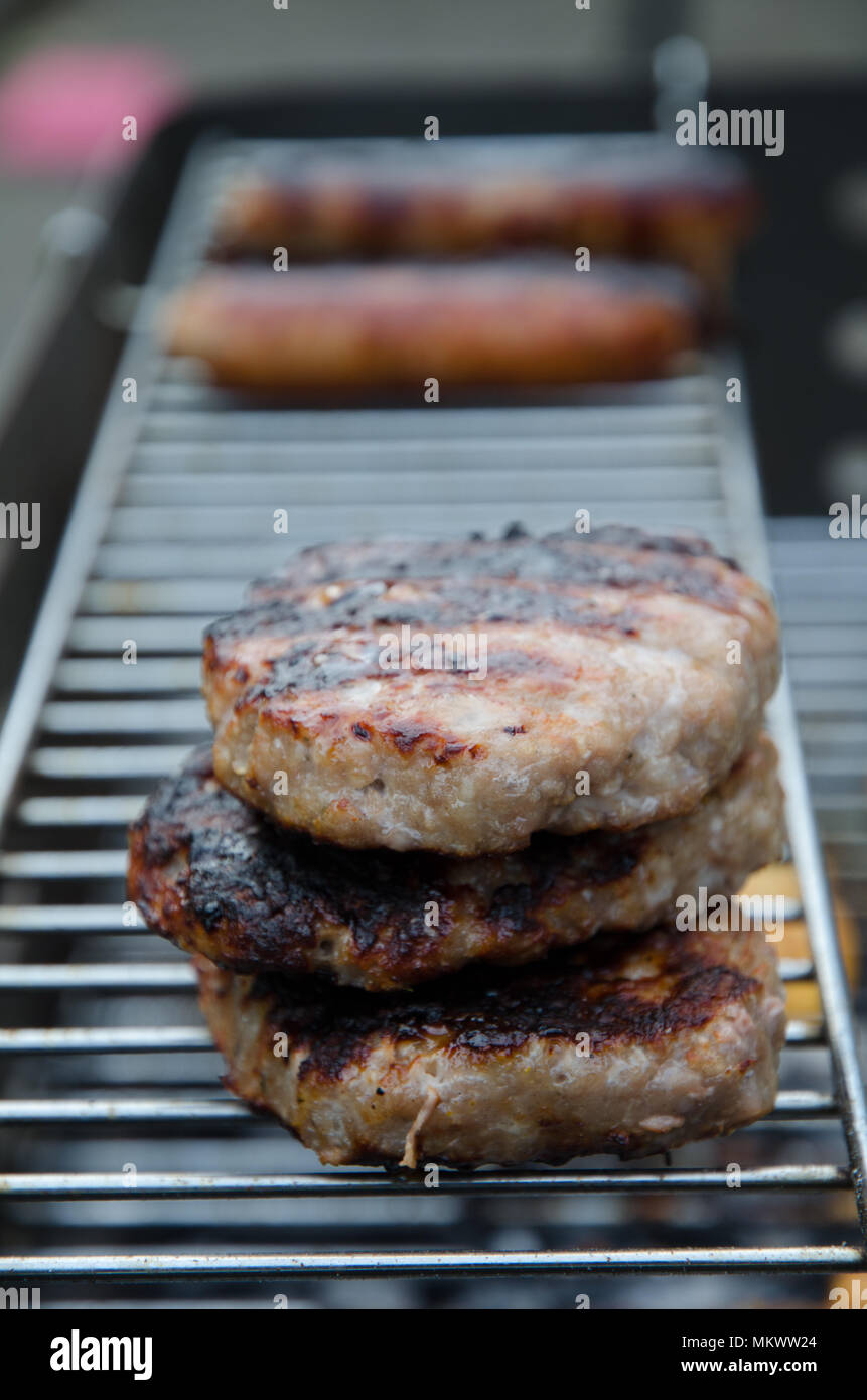 Burger und Würstchen grillen auf einem Grill Stockfoto