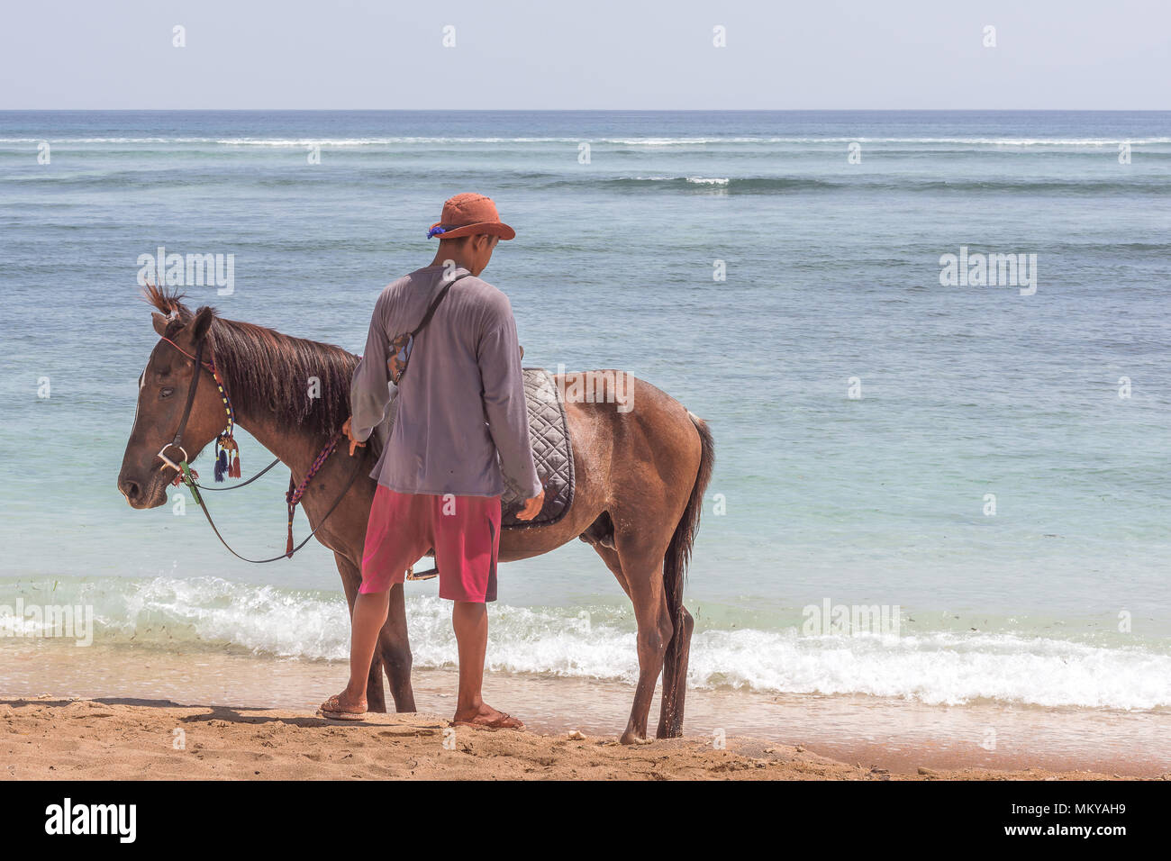 Ein indonesischer Mann und sein Pferd allein am Strand, 24. April 2018, Gili Trawangan, Indonesien Stockfoto