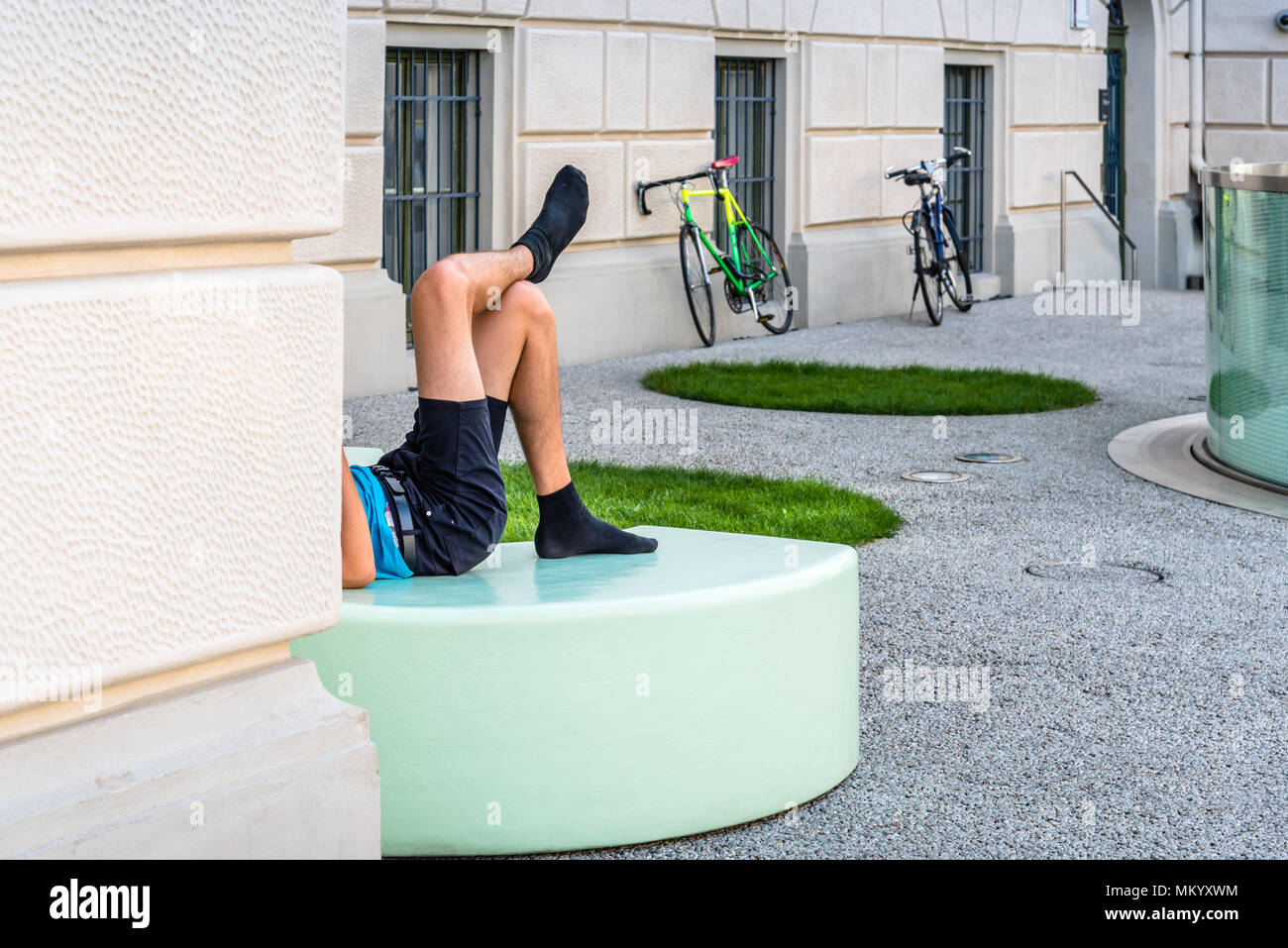 Männliche Radfahrer entspannen auf modernes Design Bank in der europäischen Stadt Stockfoto