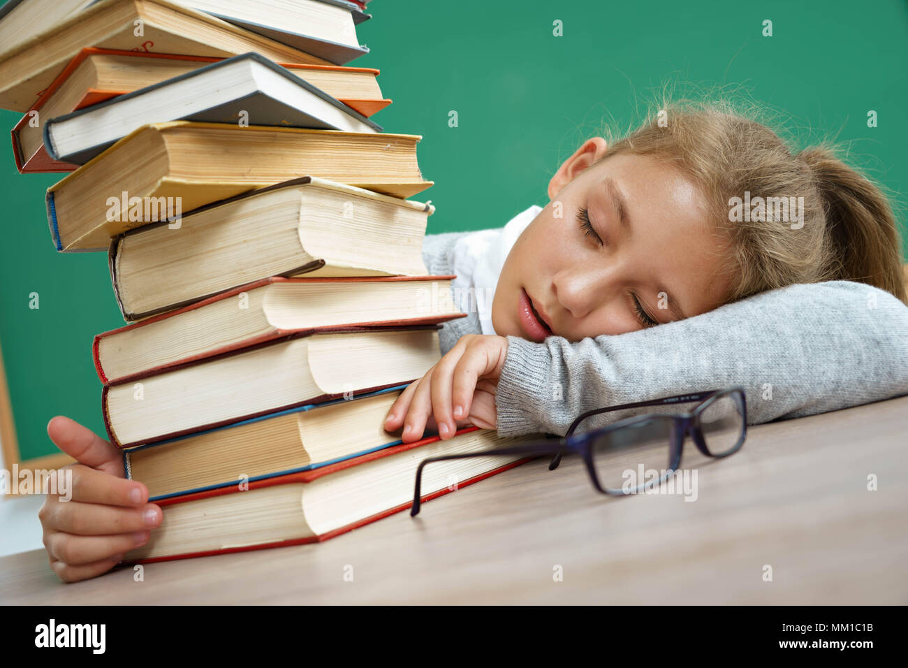 Müde Schule Mädchen schlief auf dem Tisch unter Bücher. Foto von Mädchen in der Schule. Bildung Konzept Stockfoto