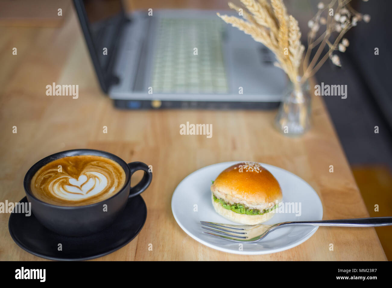 Mini Hamburger mit Kaffeetasse und Laptop am Tisch Stockfoto