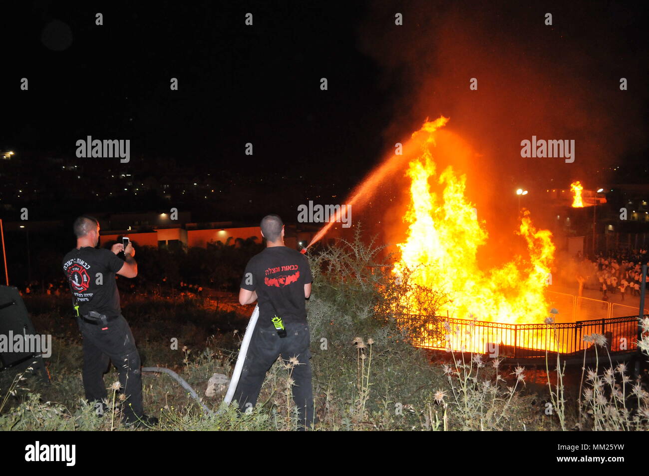 Feuerwehrmann ein großes Lagerfeuer, während die Lag B'Omer feiern (Lag B'Omer ist ein Tag für Lagerfeuer feiern löschen.) Stockfoto