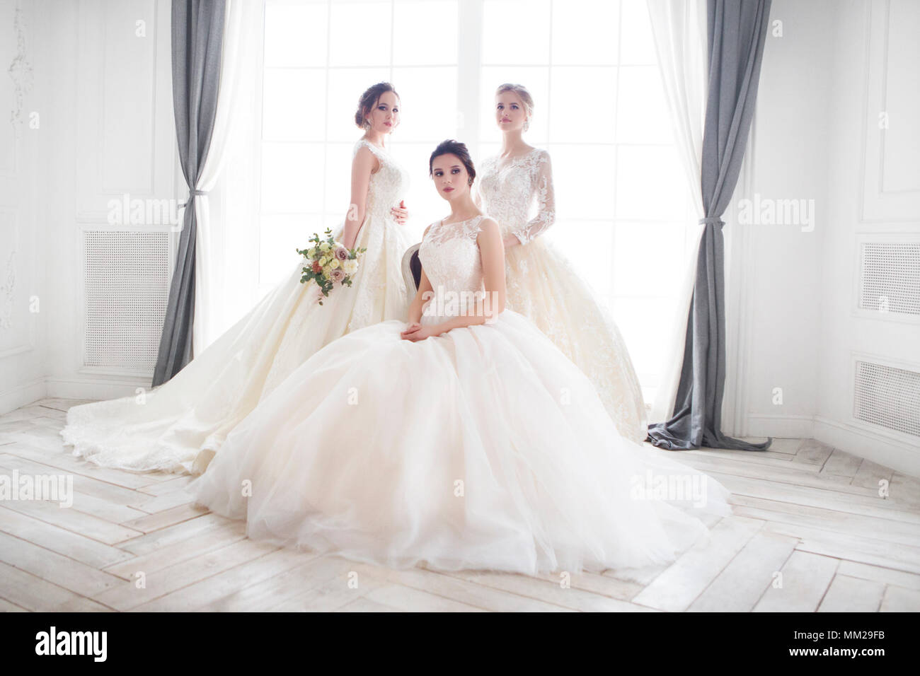 Drei junge Frau mit Blumensträuße tragen Brautkleider Stockfoto