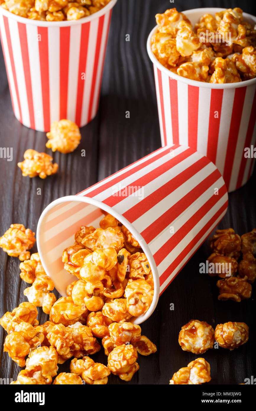 Karamell Popcorn in gestreiften box close-up auf Holz- Hintergrund. Vertikale Stockfoto