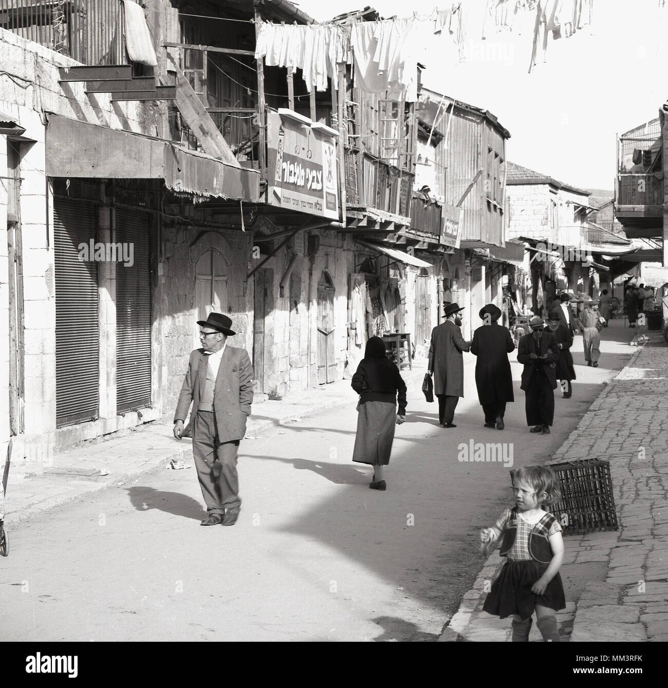 1950, historische, jüdische Menschen nach unten wandernde einer Seitenstraße der Altstadt, Jerusalem, Israel Vergangenheit die Kaufleute Wohnräume und unter einer Wäscheleine. Stockfoto