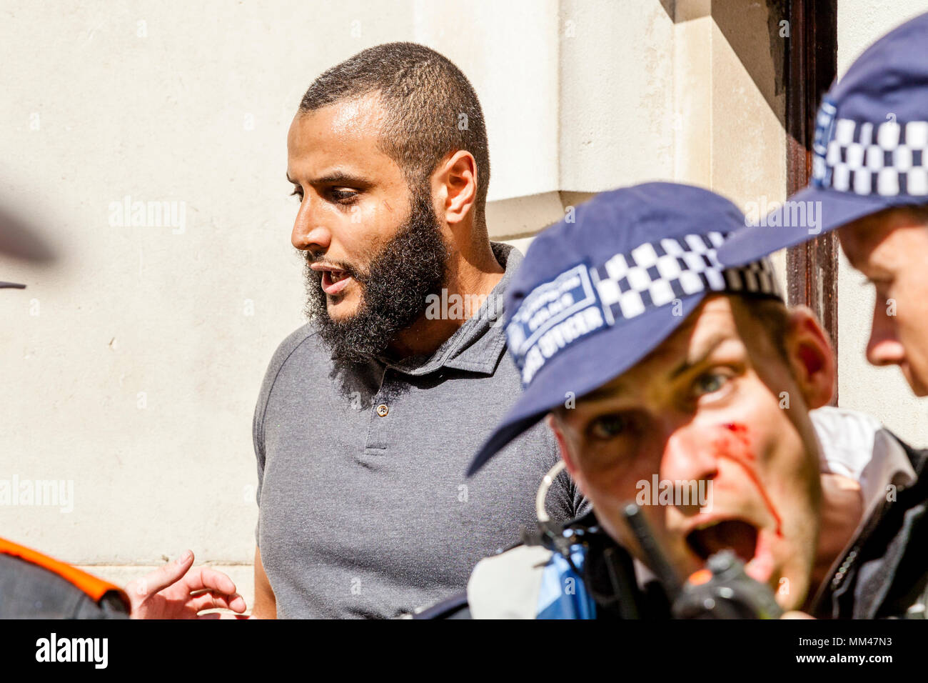 Eine verletzte Metropolitan Police Officer Escorts prominente Muslimische Sprecher Muhammed Hijab entfernt von einer Freiheit der Rede Rally, London, UK Stockfoto