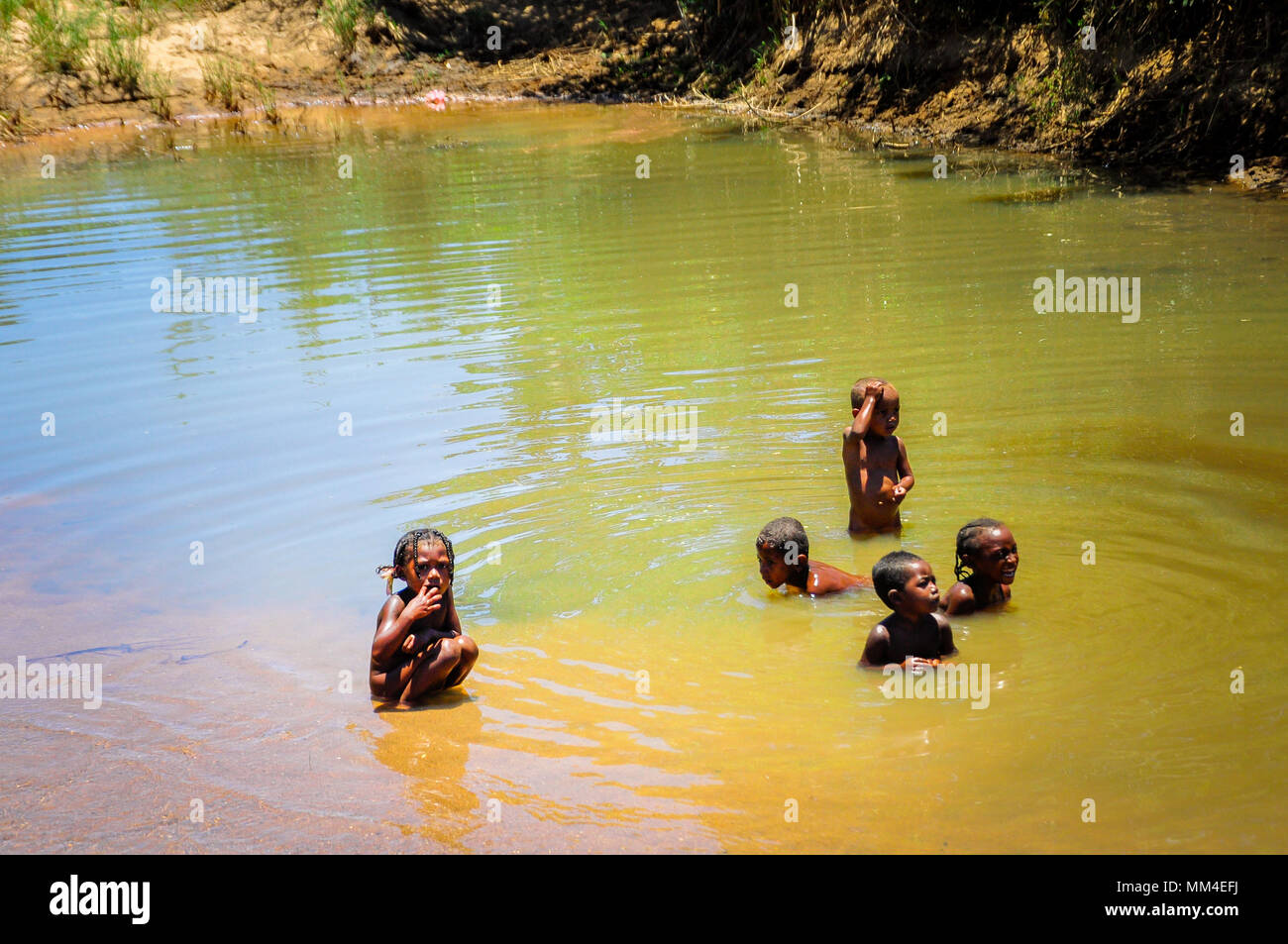 Einige unbekannte Kinder spielen in einem Teich schmutziges Wasser. Madagaskar ist eines der ärmsten Länder der Erde Stockfoto