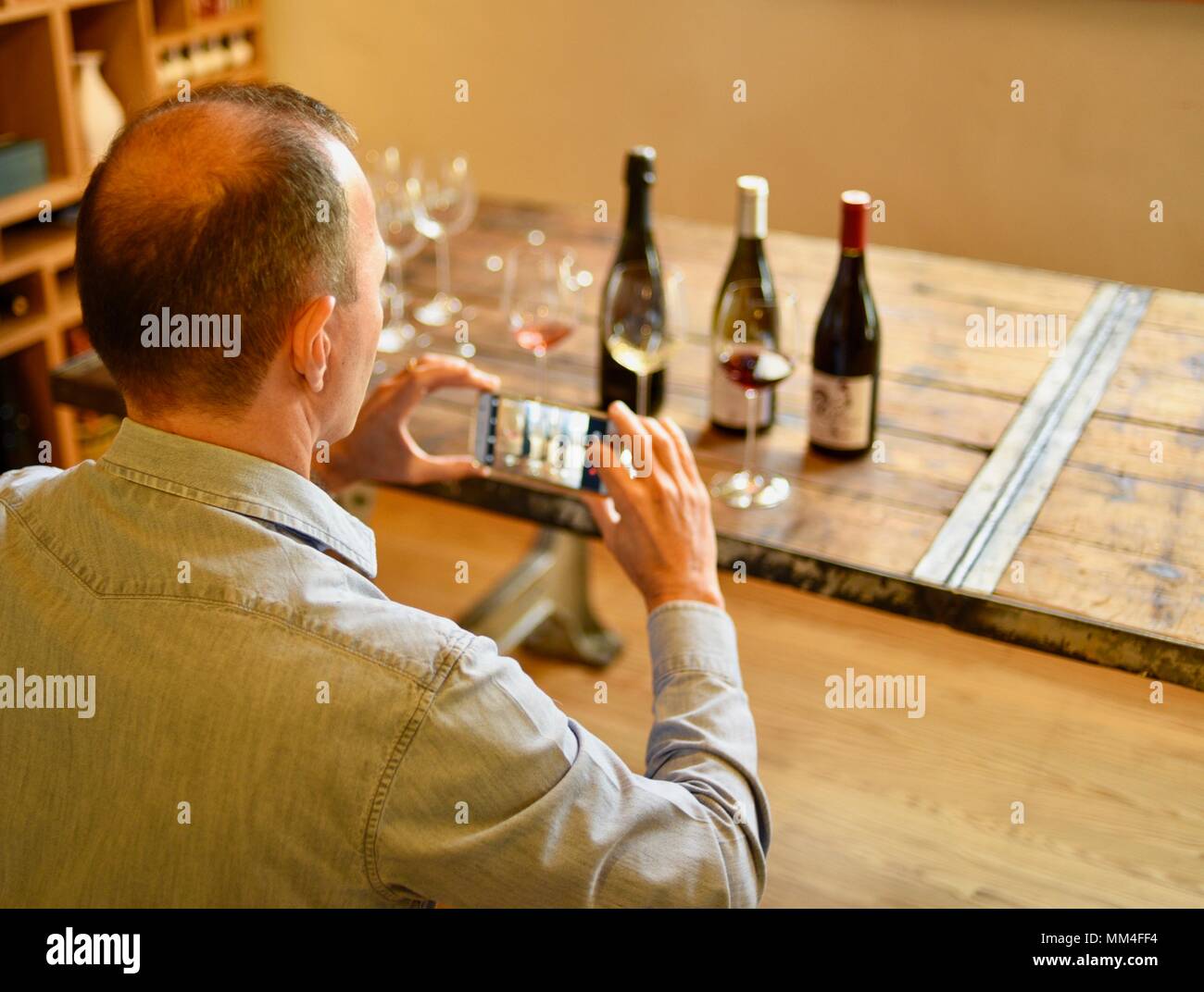 Mann, die Smart Handy Fotos von Wein Gläser und Flaschen während der Weinprobe im La Bergerie, Texas Hill Country, Fredericksburg, Texas, USA Stockfoto