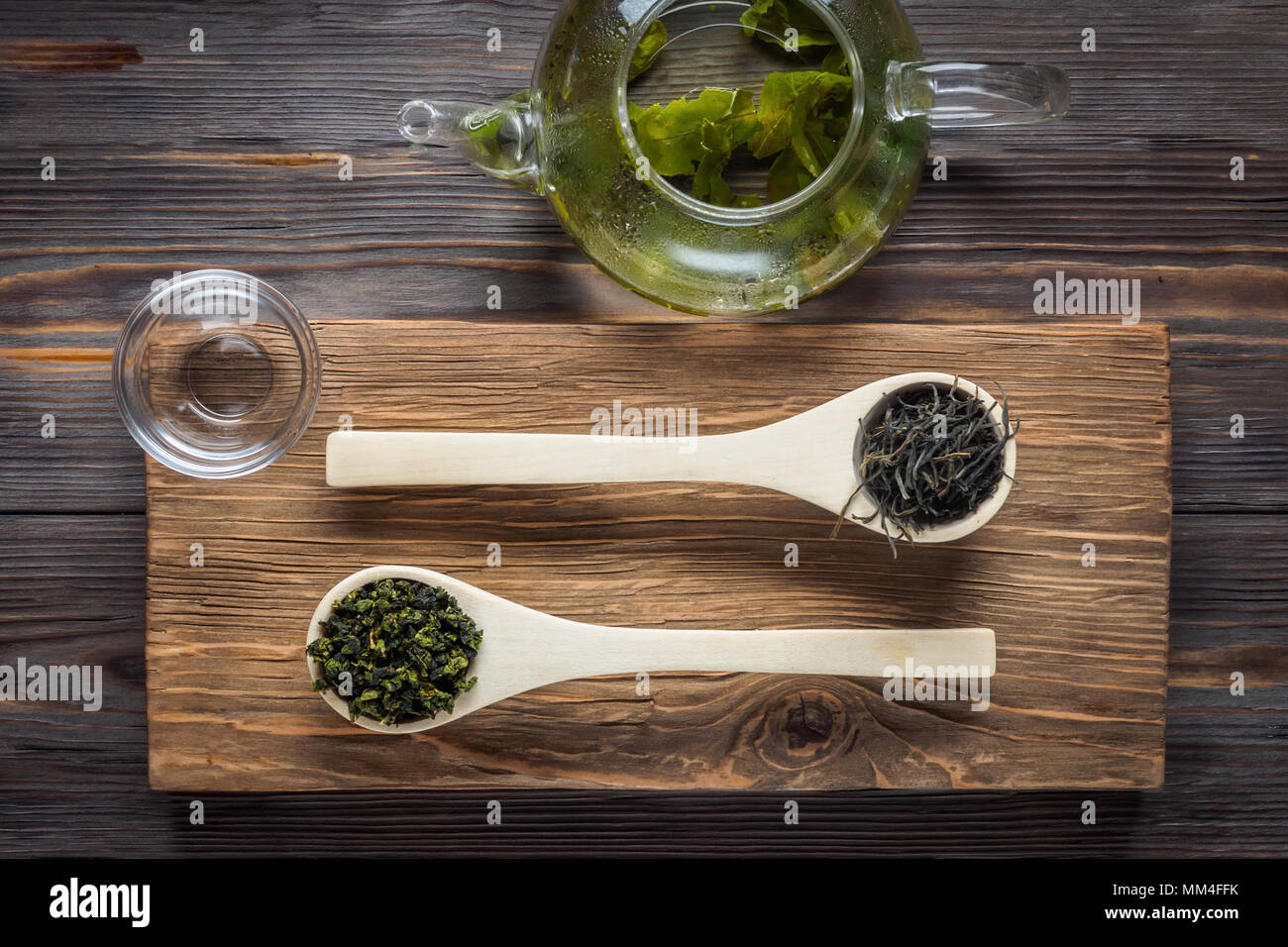 Traditioneller Chinesischer grüner Tee verschiedene Gärung Holz- kulinarische Löffel Teekanne mit frisch gebrühtem Blätter auf dunklen Tabelle Low Key essen Konzept top vie Stockfoto