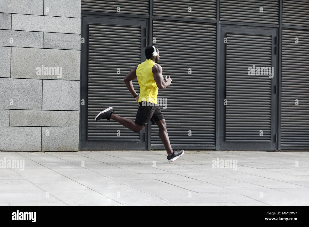 Sport, Fitness Concept. Sportliche Mann im gelben T-Shirt mit Sonnenuntergang im Freien, Feder, attraktive dunkelhäutige Läufer Joggen im Park Stockfoto