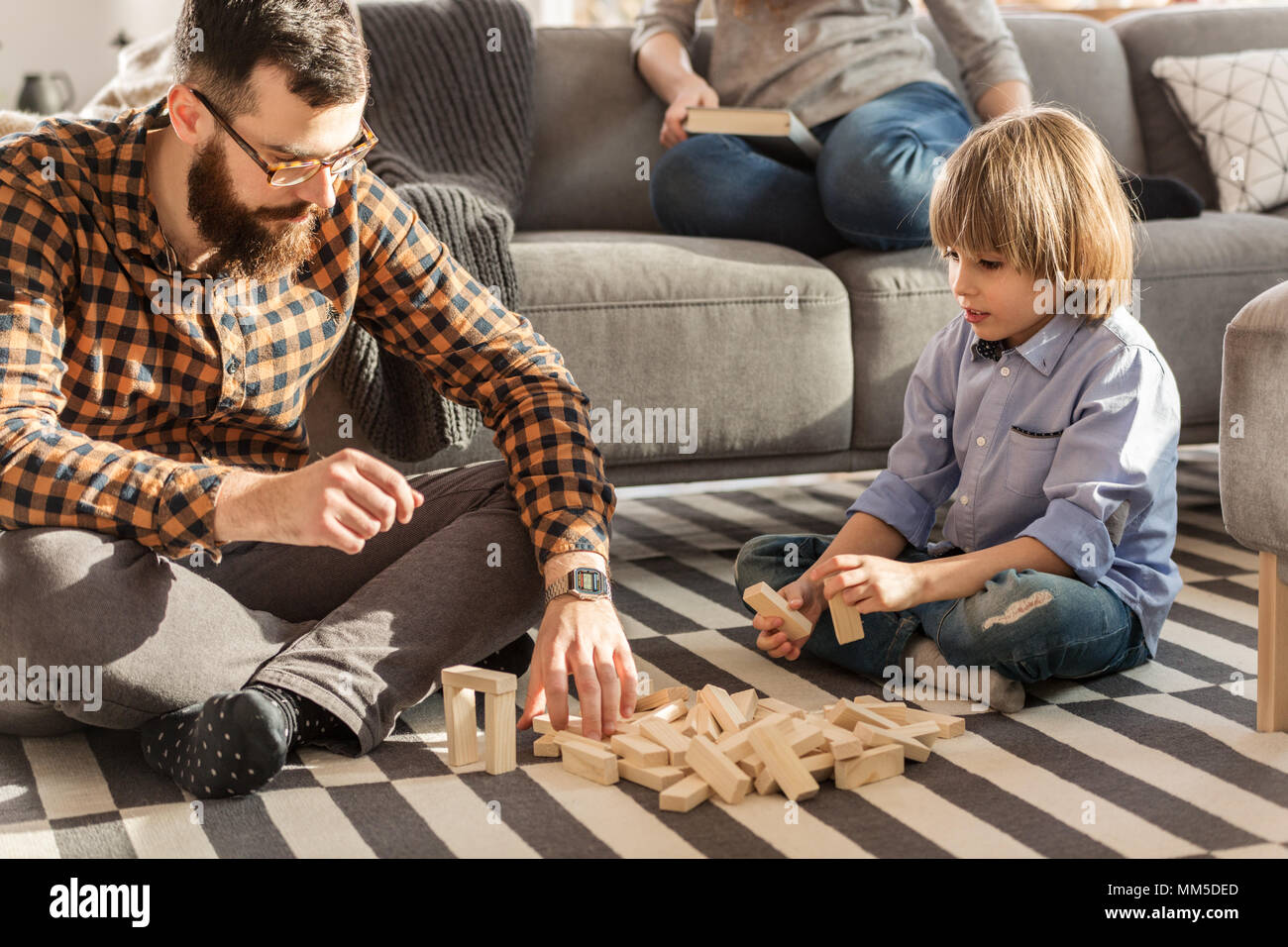 Vater Anordnen von Holz- Ziegel mit seinem Sohn beim Sitzen auf dem Teppich Stockfoto
