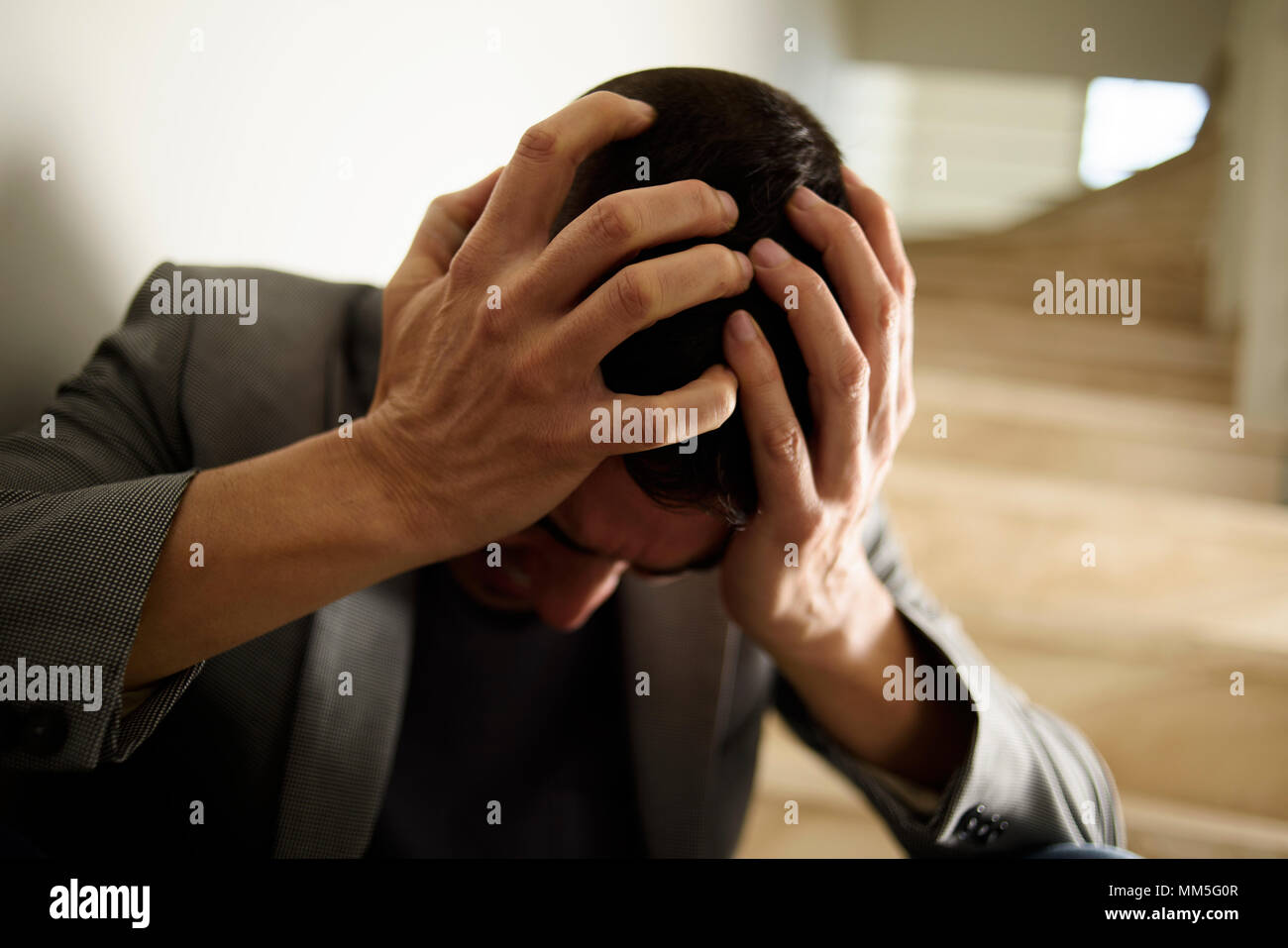 Nahaufnahme eines verzweifelten jungen kaukasischen Mann mit seinen Händen in seinem Kopf. Stockfoto