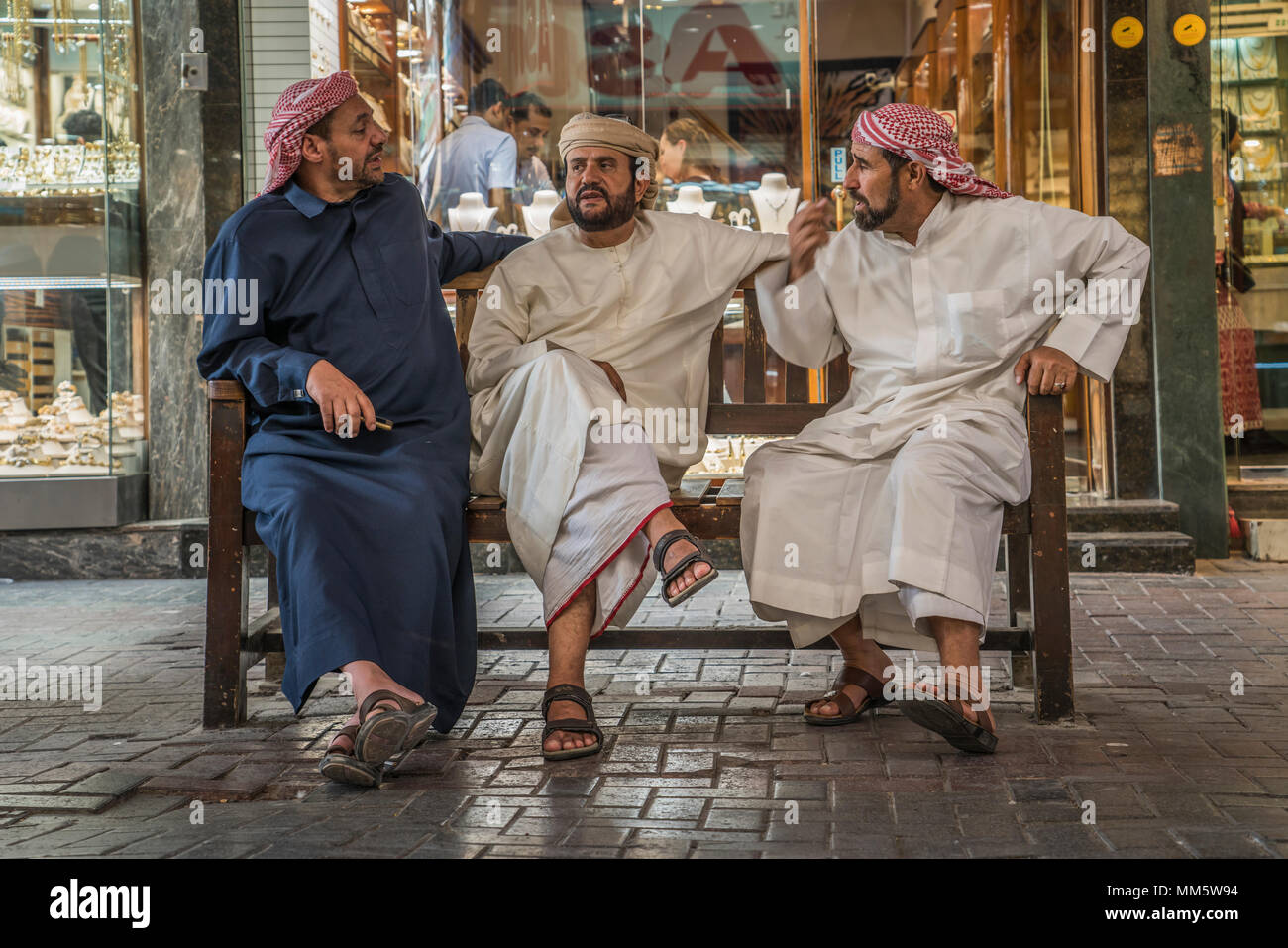 Eine Gruppe von Männern in den Arabischen traditionelles Kleid unterhalten im goldmarkt der Altstadt Souk von Dubai, Vereinigte Arabische Emirate, Naher Osten. Stockfoto