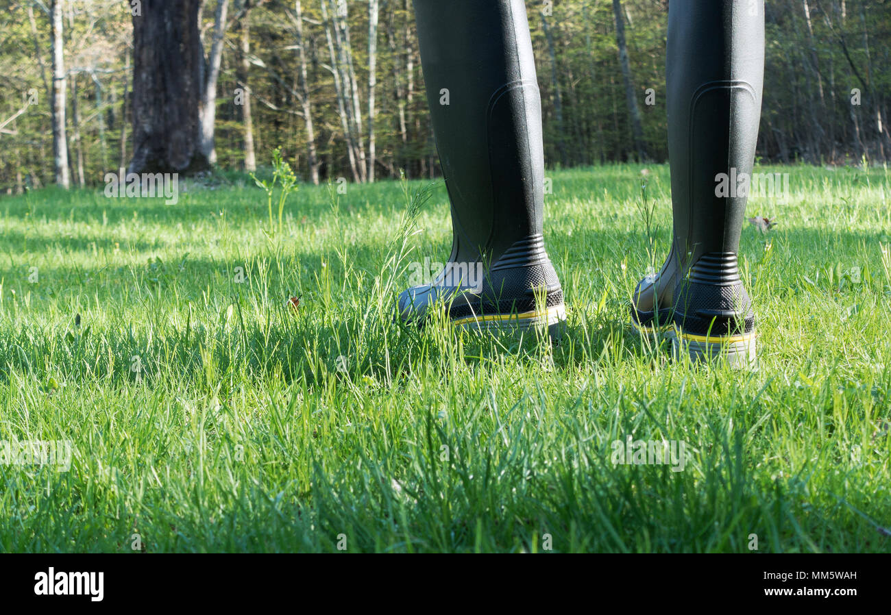 Person in Gummi Schuhe Wandern im Gras Stockfoto