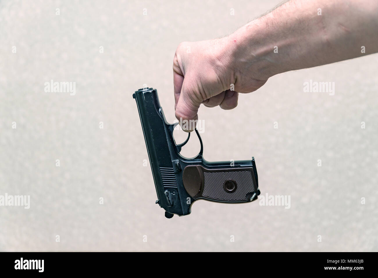 Mann, der das Gewehr mit zwei Fingern auf grauem Hintergrund Stockfoto