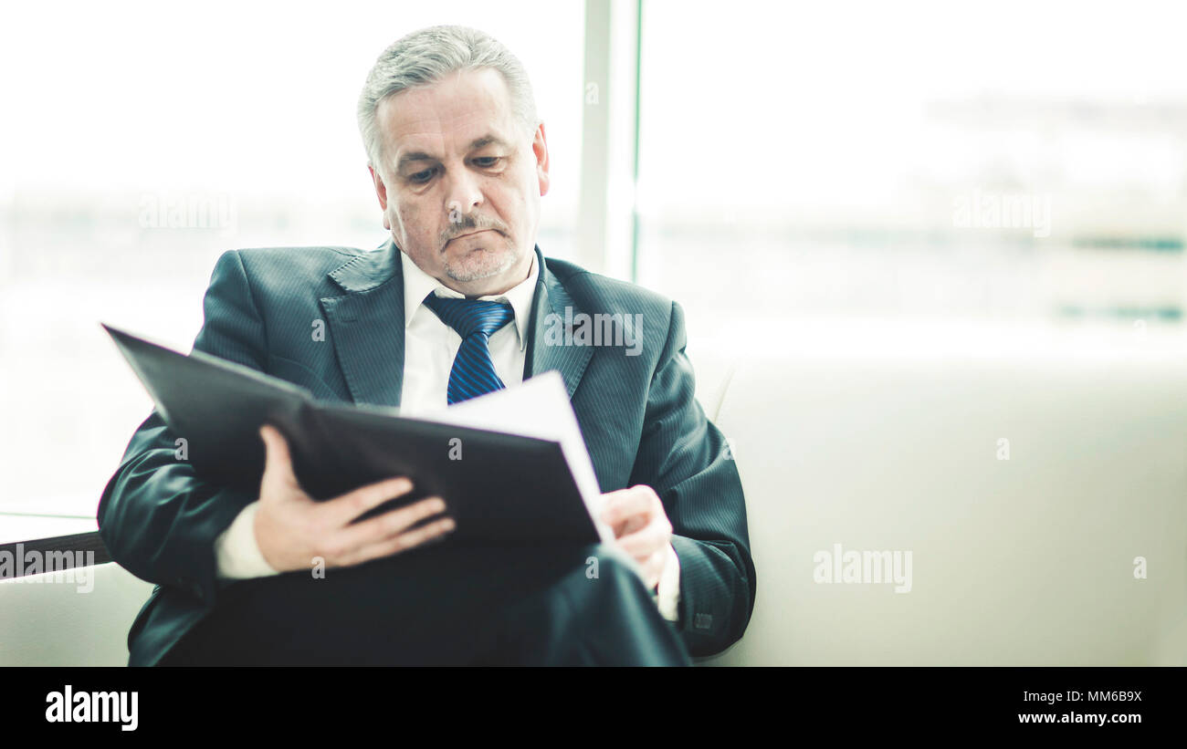 Erfolgreicher Geschäftsmann Studien Working Papers auf dem Sofa sitzen im eigenen Büro Stockfoto