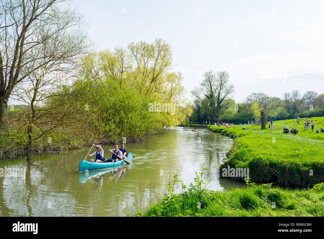 Drei Männer Kanu auf dem Fluss und Menschen entspannend am Ufer im Grantchester Meadows Riverside Park, entlang des Flusses Cam (auch als Zuschuss Stockfoto