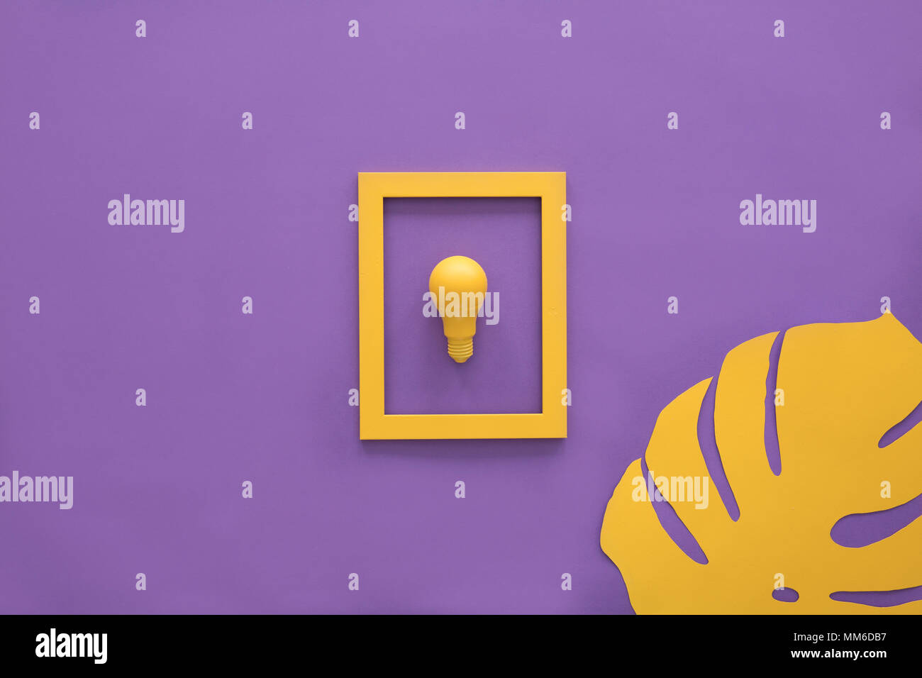 Gelbe Lampe in einem Frame auf lila Hintergrund mit einem Blatt auf es Stockfoto