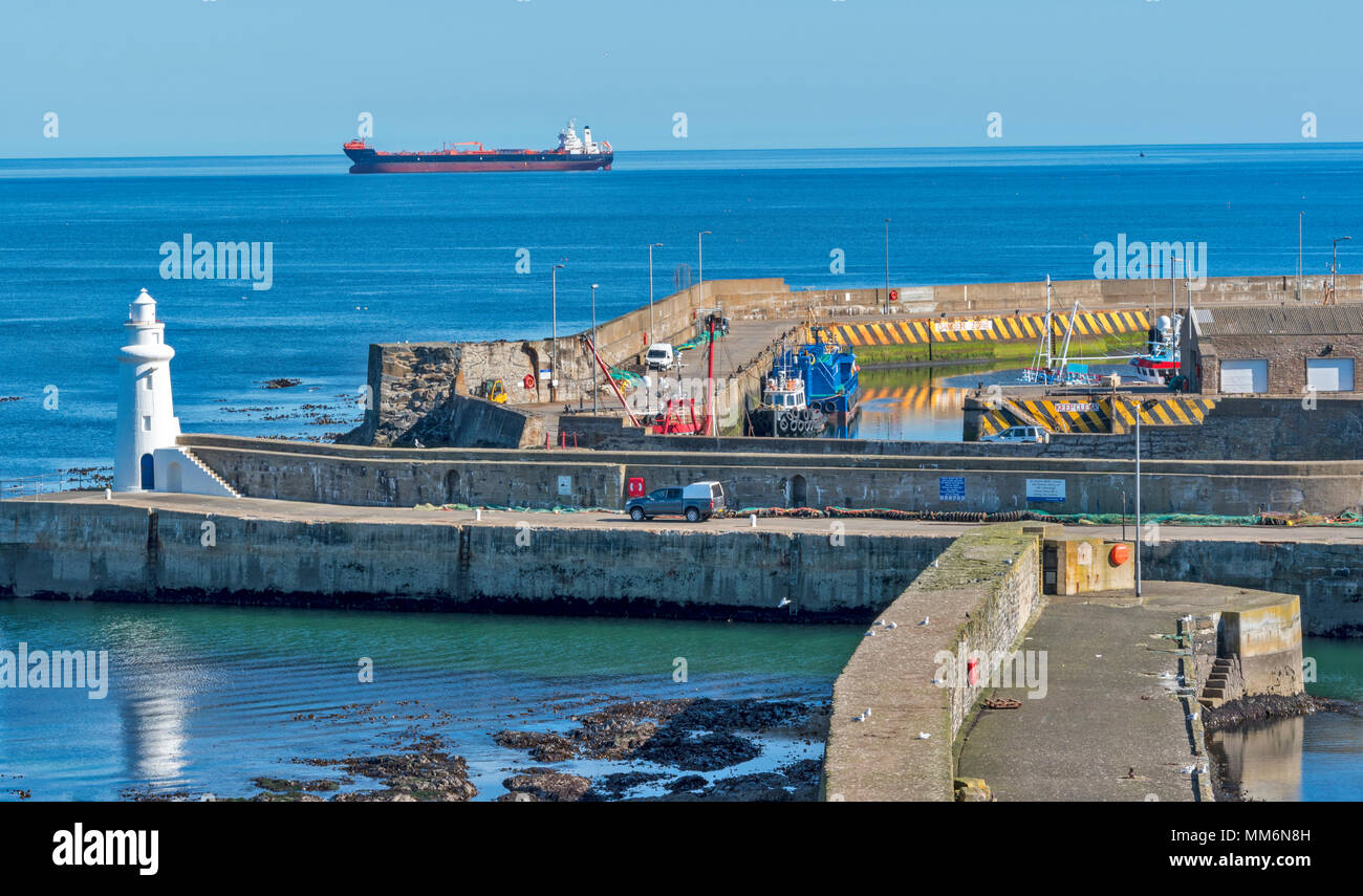 MACDUFF ABERDEENSHIRE SCOTLAND WERFT oder Werft die weißen Leuchtturm an der Hafeneinfahrt und großes Schiff vor Anker liegend aus macduff Stockfoto