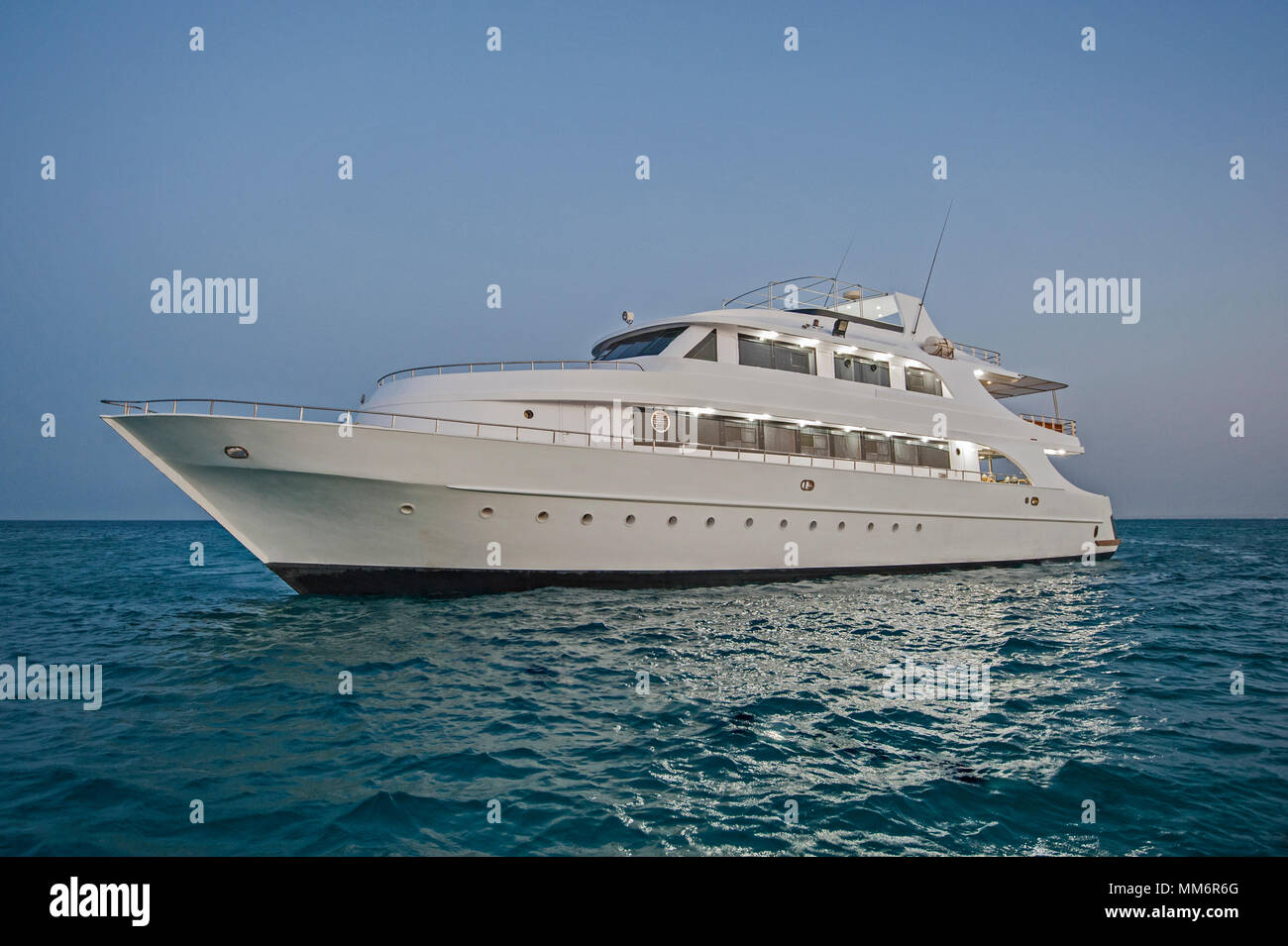 Große private Luxury Motor yacht Yacht segeln auf einem tropischen Meer leuchtet in der Dämmerung Stockfoto