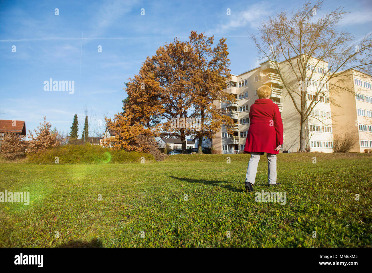 Alte Frau zu Fuß auf Wiese in der Nähe von Häusern Stockfoto