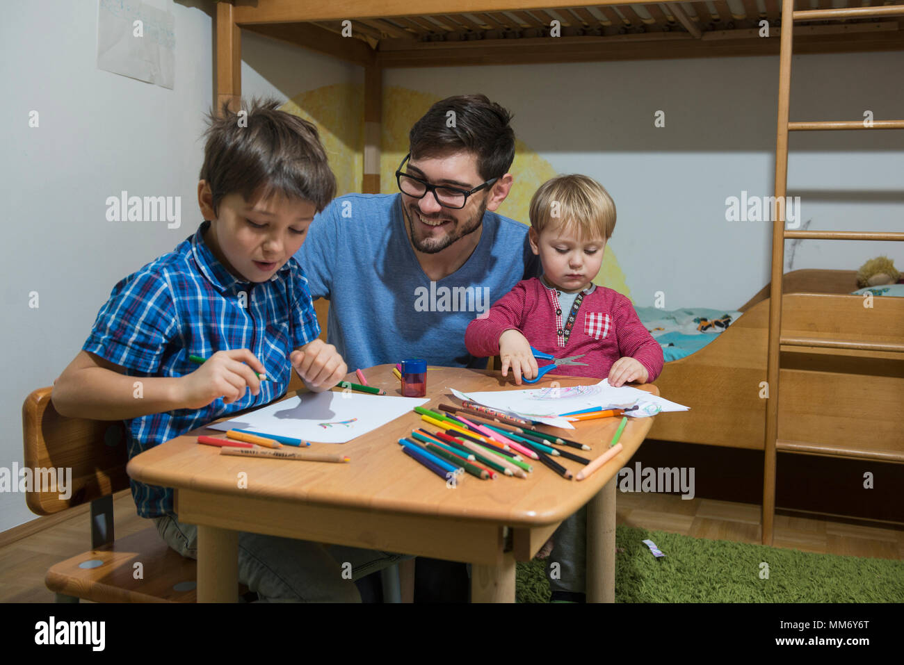 Genießen Brüder mit Buntstiften zu zeichnen, während Vater lächelt, München, Deutschland Stockfoto