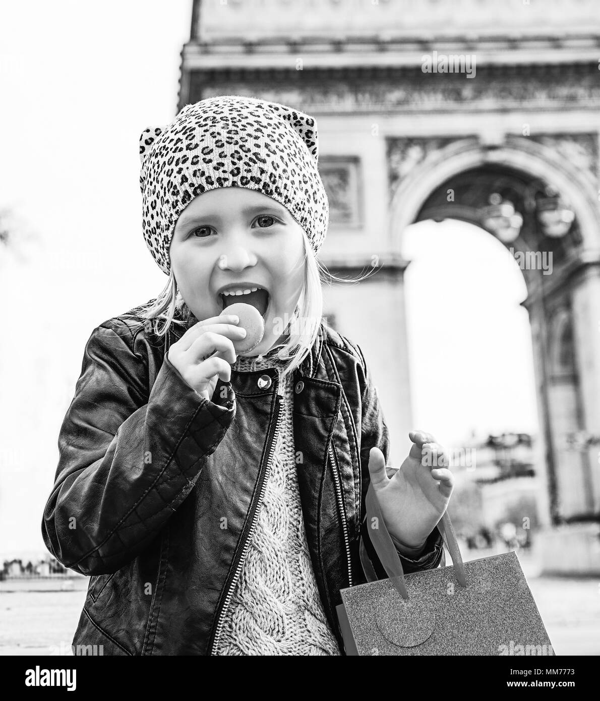 Stilvolle Herbst in Paris. lächelnd elegante Kind mit roten vorhanden Tasche in der Nähe von Arc de Triomphe in Paris essen französisch Makronen Stockfoto