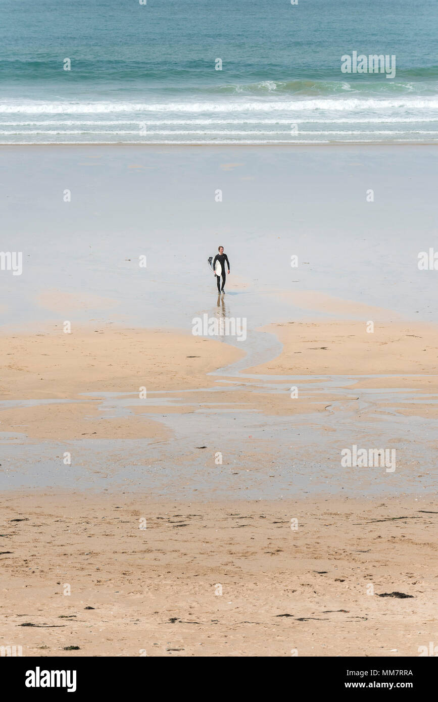 Ein einsamer Surfer sein Surfbrett tragen und von dort über Fiostral Strand in Newquay in Cornwall; Stockfoto