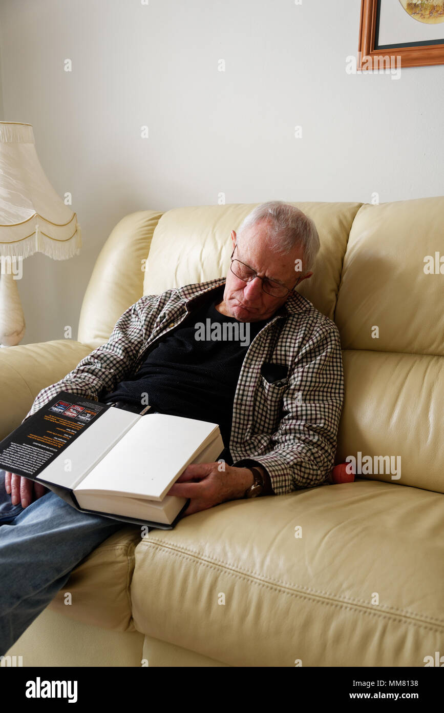 Anolder Mann schlafend auf dem Sofa gefallen beim Lesen eines Buches Stockfoto