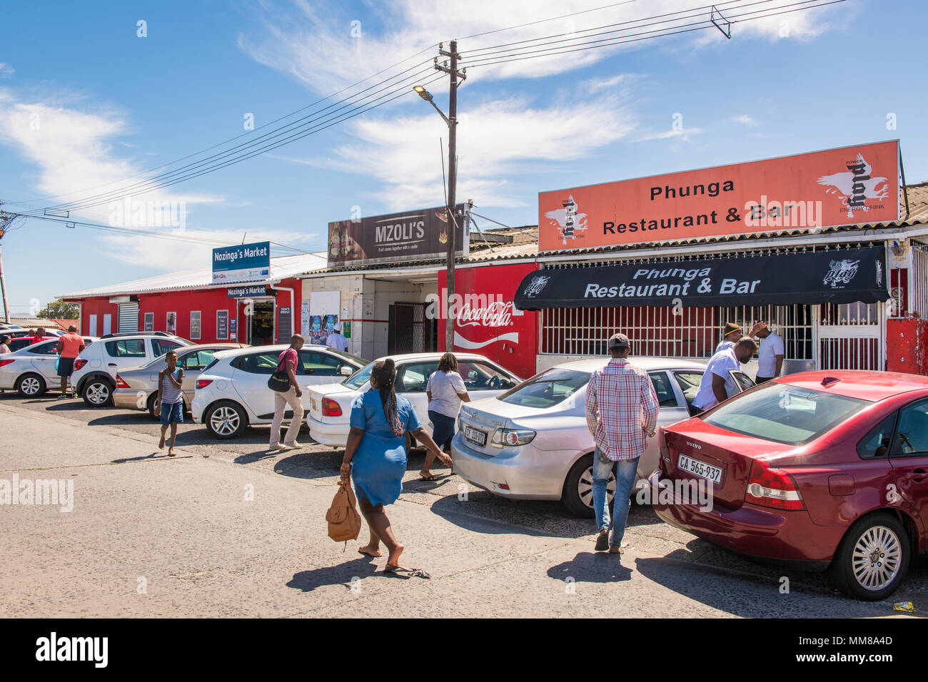 Ein Cluster von Autos sitzt außerhalb der lokalen Unternehmen wie Menschen Mühle in Guguletu Township in Kapstadt, Südafrika Stockfoto