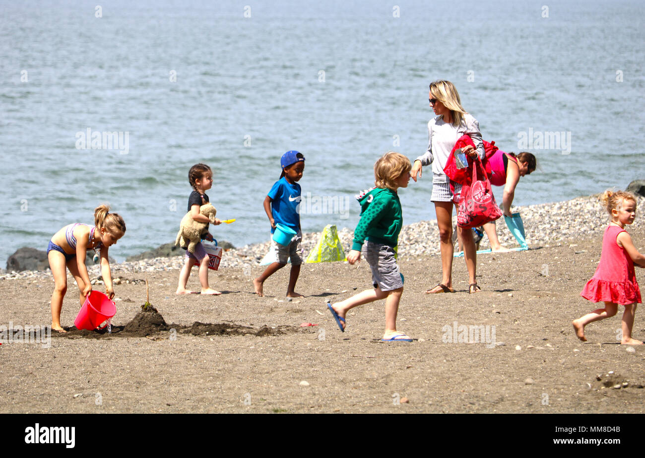Kinder am Strand spielen am Boulevard Park in Fairhaven, Bellingham, Washington, USA. Ein junges Mädchen ist leer er Wassereimer in den Sand whil Stockfoto