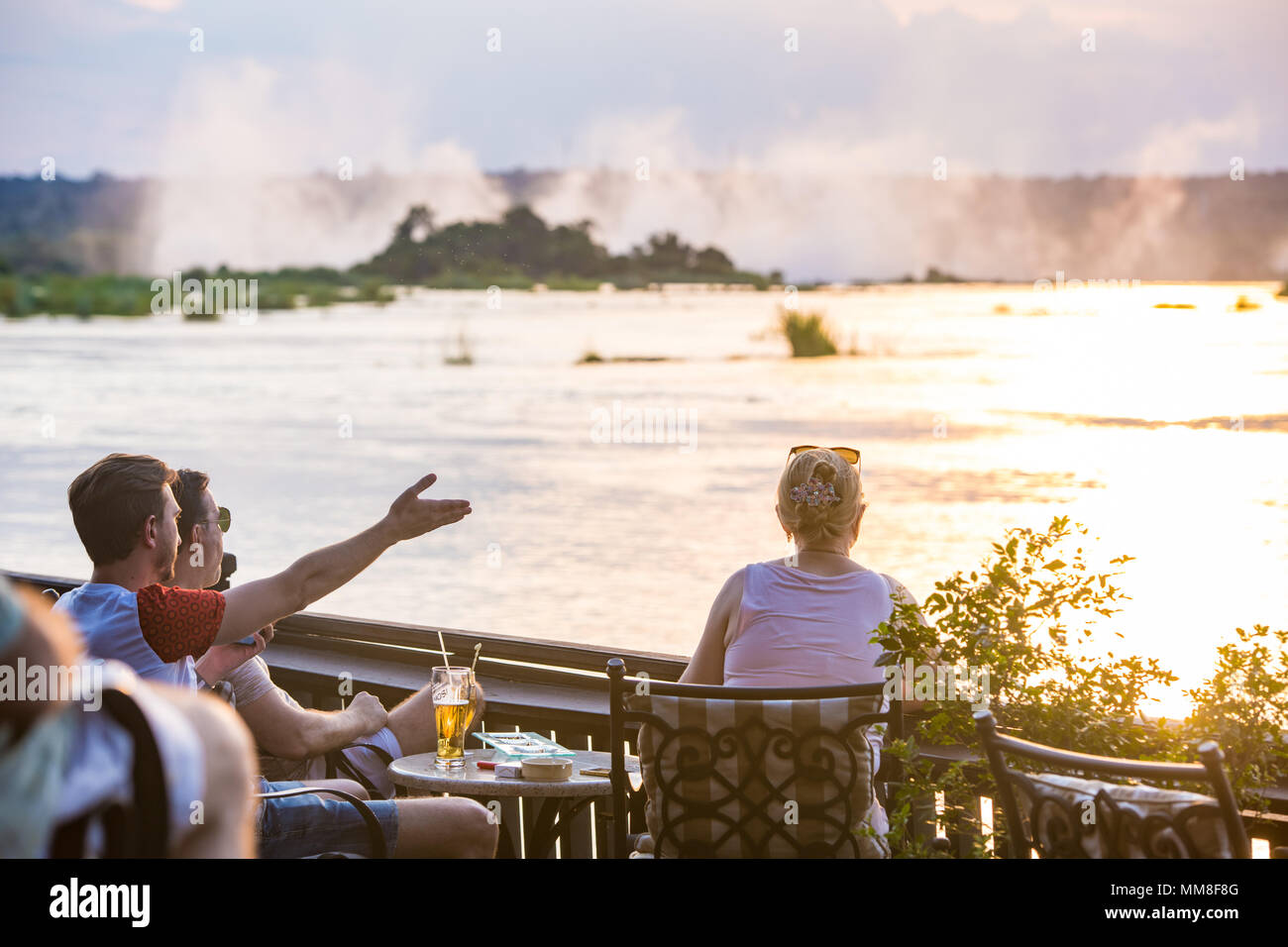 Eine Gruppe von Hotel die Gäste des Royal Livingstone Hotel auf der Sonnenterrasse sitzen und den Sonnenuntergang über dem Sambesi Livingstone, Sambia beobachten Stockfoto