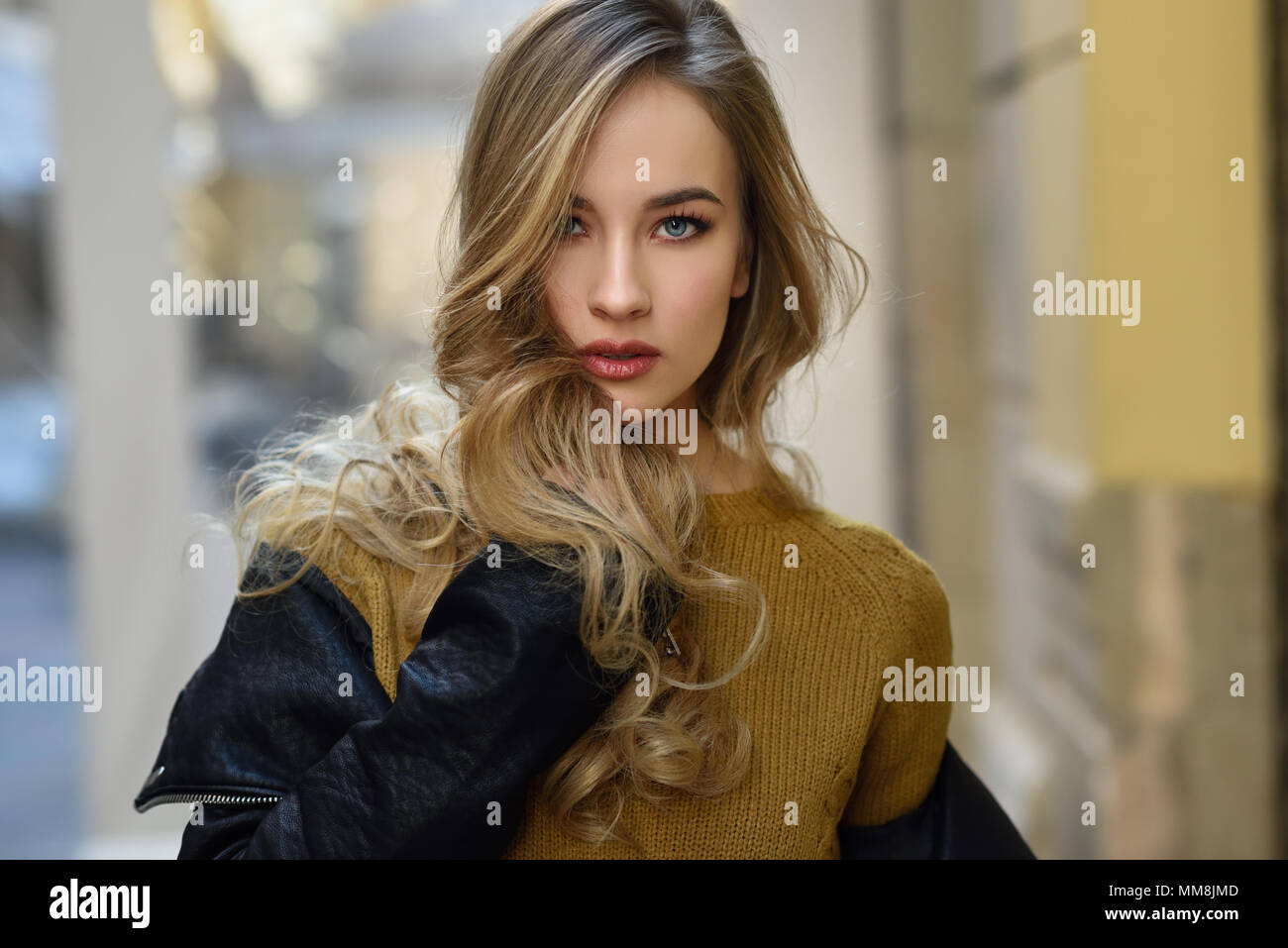 Blonde Frau im städtischen Hintergrund. Schöne junge Mädchen mit schwarzen leder jacke und mini rock auf der Straße stand. Hübsche Russische Frauen mit Stockfoto